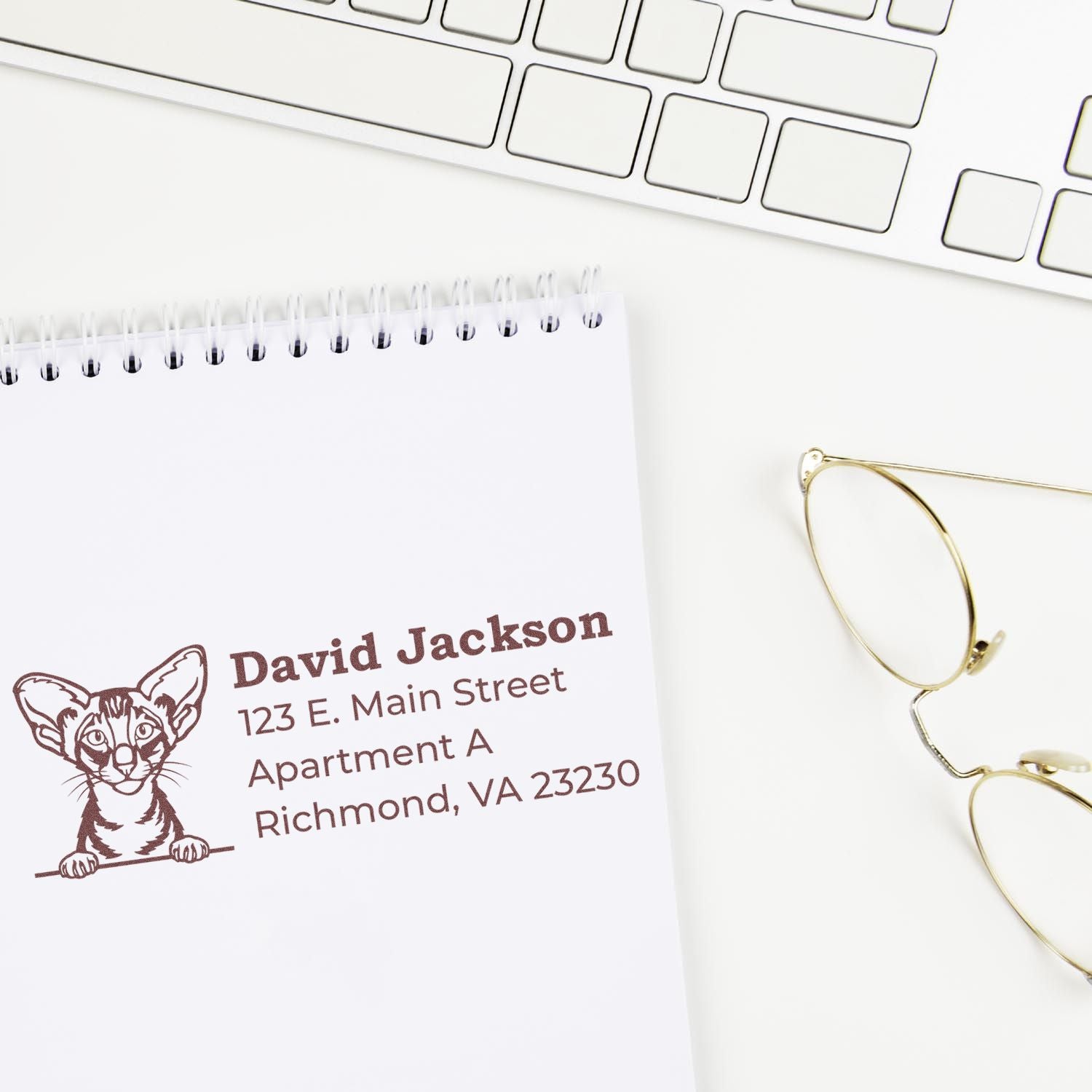 Wood Handle Oriental Shorthair Cat Address Stamp on white paper, featuring a cat illustration and sample address. Nearby are a keyboard and glasses, creating a tidy workspace setting.