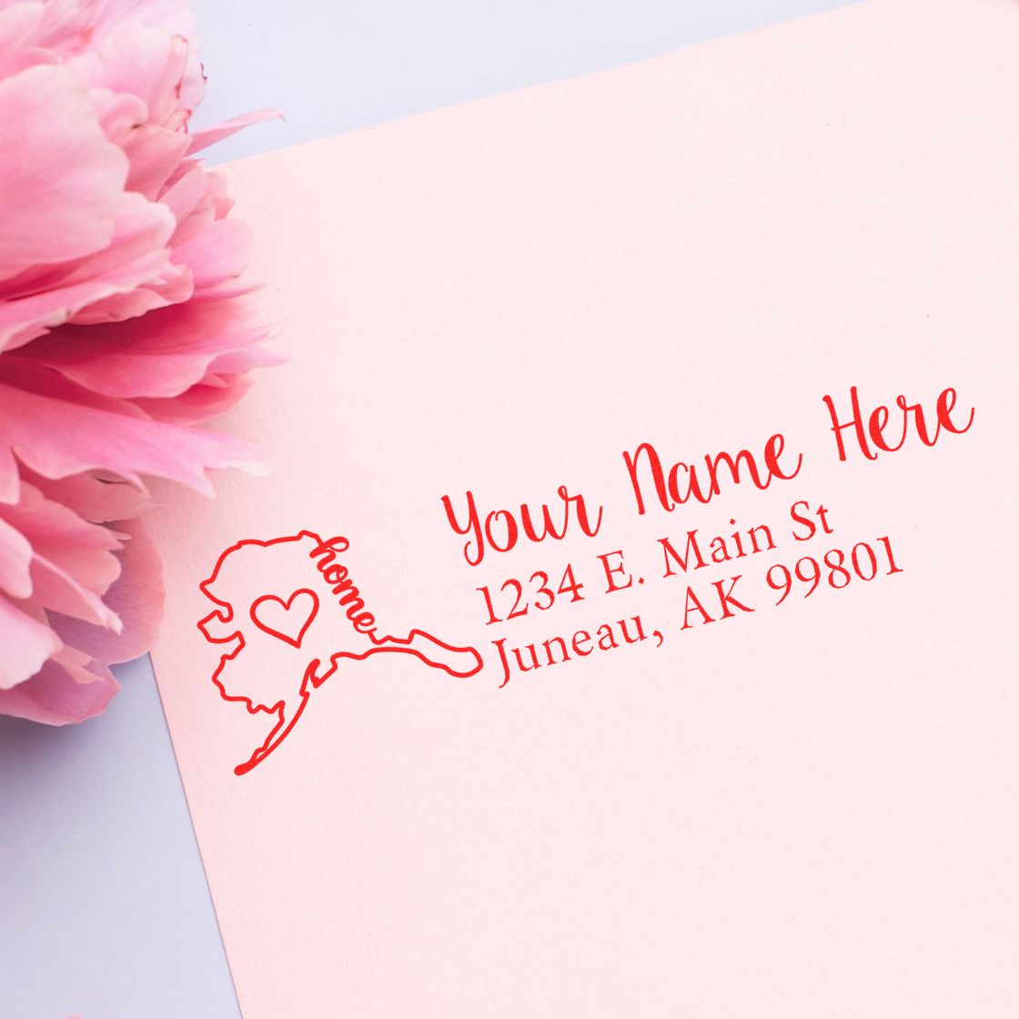 PSI Pre-Inked Personalized Alaska State Love Address Stamp on pink paper with a peony. Features a heart design on Alaska map and customizable address text in red.