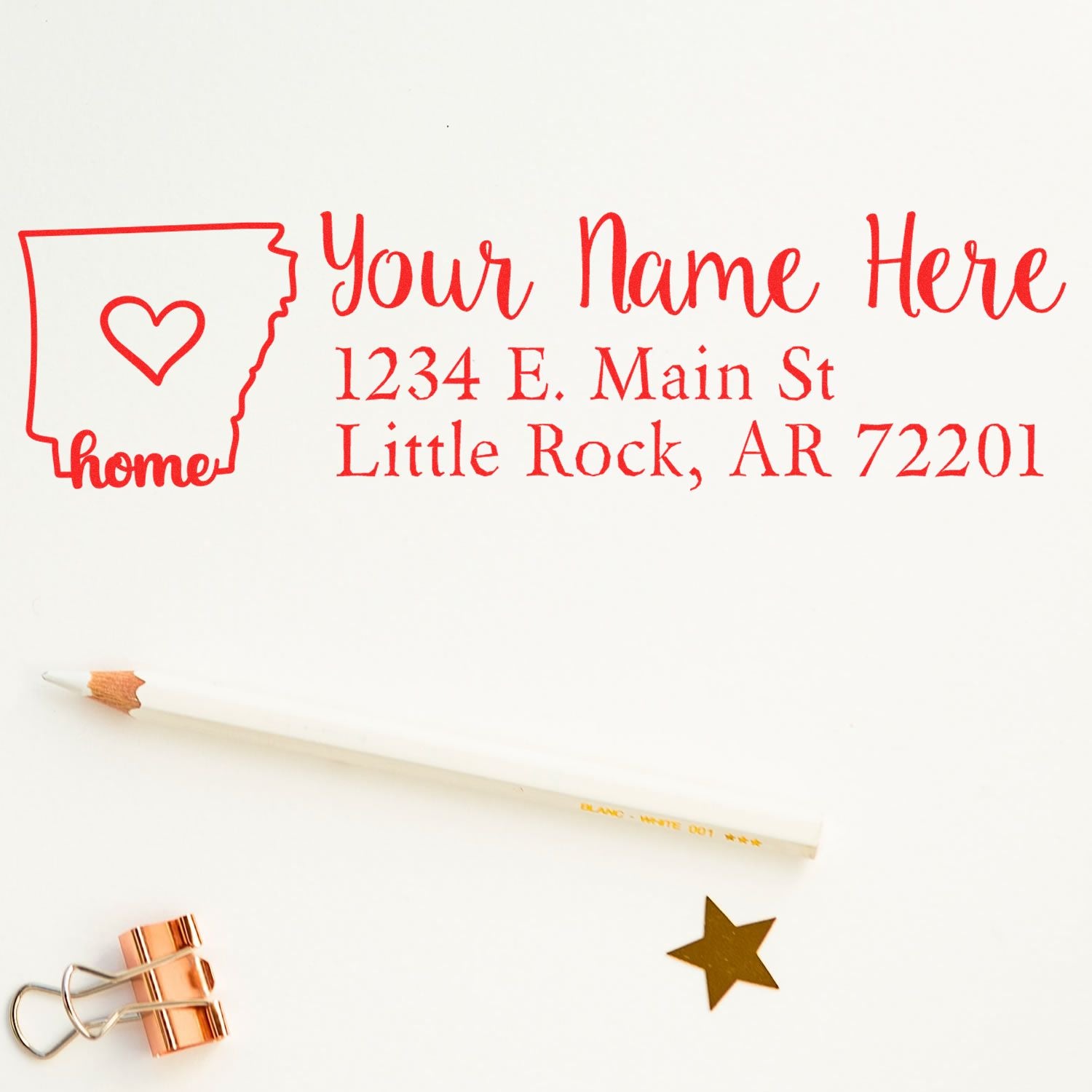 Arkansas Self-Inking State Love Address Stamp with a red outline of Arkansas and heart, personalized address, pencil, gold star, and clip on a white background.