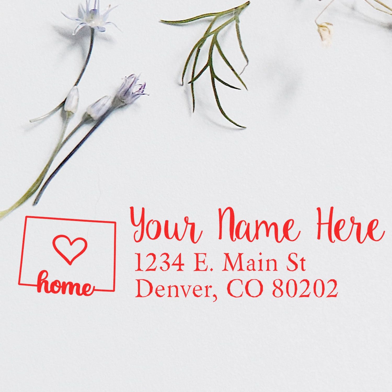 PSI Pre-Inked Personalized Colorado State Love Address Stamp in red ink on white paper, featuring a heart and home design, with delicate flowers nearby.