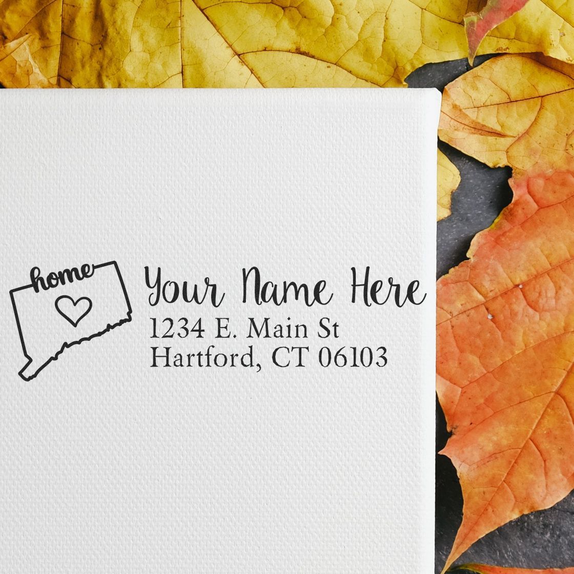 Connecticut Self-Inking State Love Address Stamp on white paper with Your Name Here and a heart in the state outline, surrounded by autumn leaves.