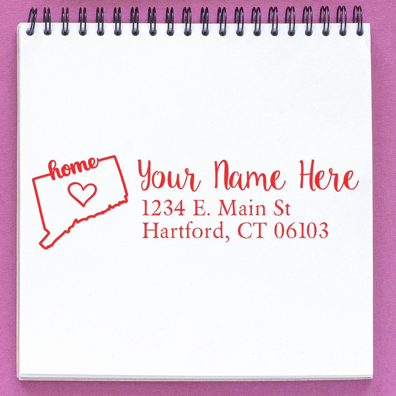 Connecticut Self-Inking State Love Address Stamp on a notepad, featuring a red outline of Connecticut with a heart and customizable address text in elegant script.