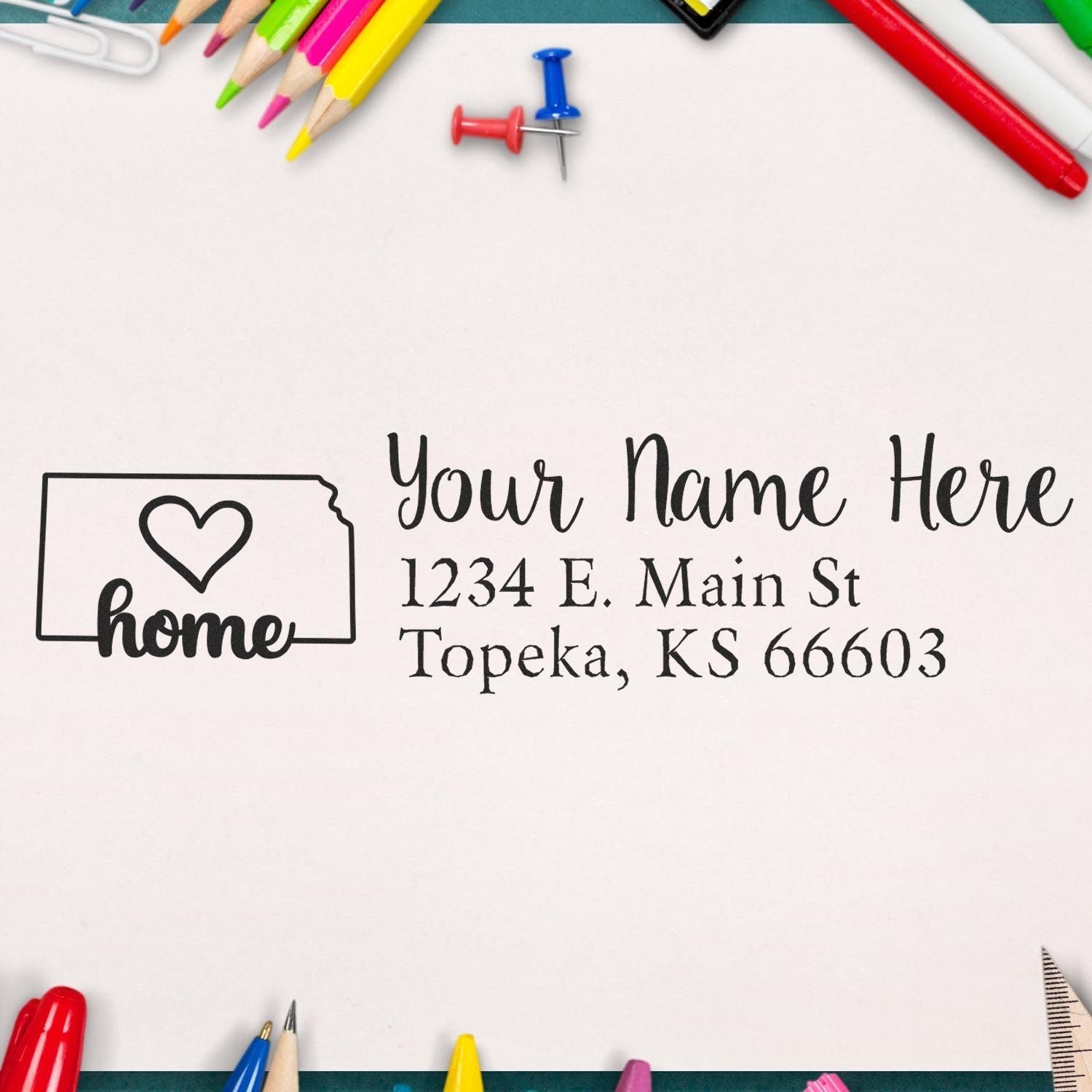 PSI Pre-Inked Personalized Kansas State Love Address Stamp on paper with Your Name Here and a heart design, surrounded by colorful stationery items like pencils and push pins.