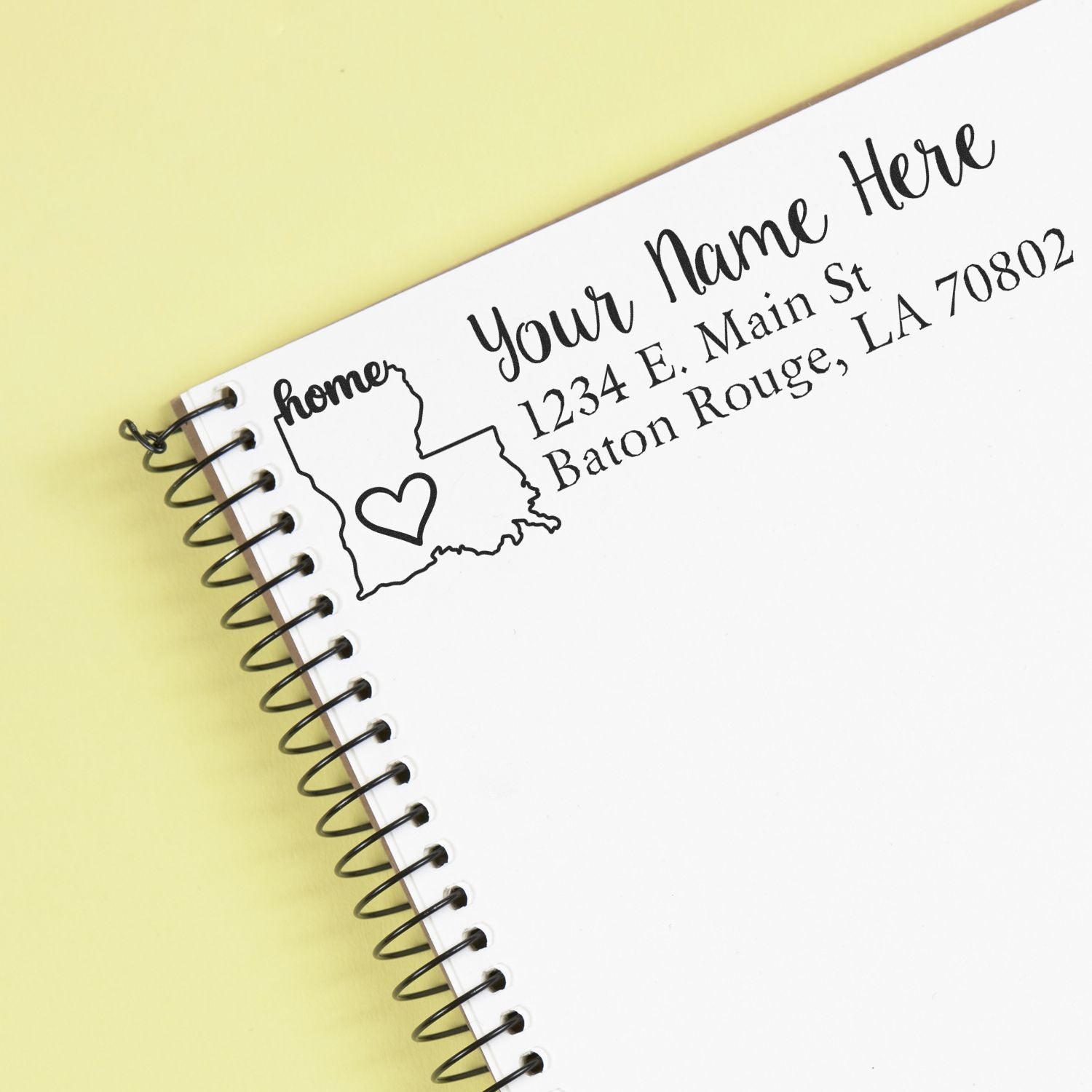 Louisiana Self-Inking State Love Address Stamp on a notebook page, featuring a heart inside the state outline with customizable address text. Perfect for personalizing mail with a touch of home.