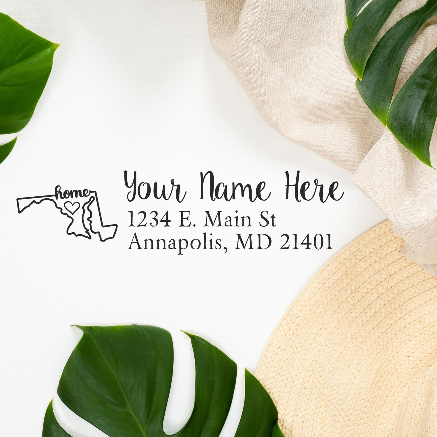 Slim Pre-Inked Maryland State Love Custom Address Stamp on white paper with green leaves and a beige hat. The stamp features a Maryland outline with home text and customizable address lines.