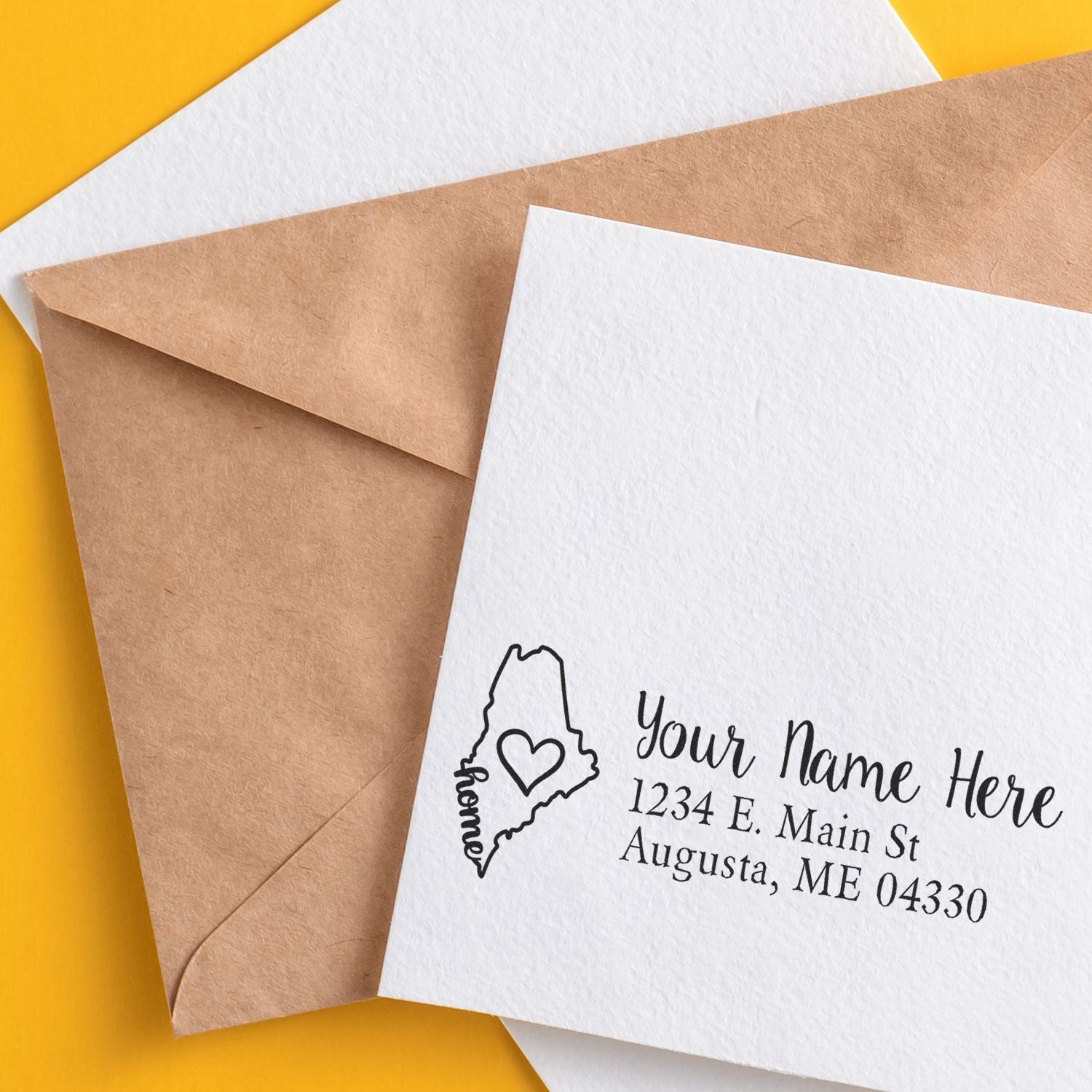 Maine Self-Inking State Love Address Stamp on a white card with a brown envelope. Features a heart inside Maine's outline, personalized with name and Augusta address. Perfect for adding a personal touch.