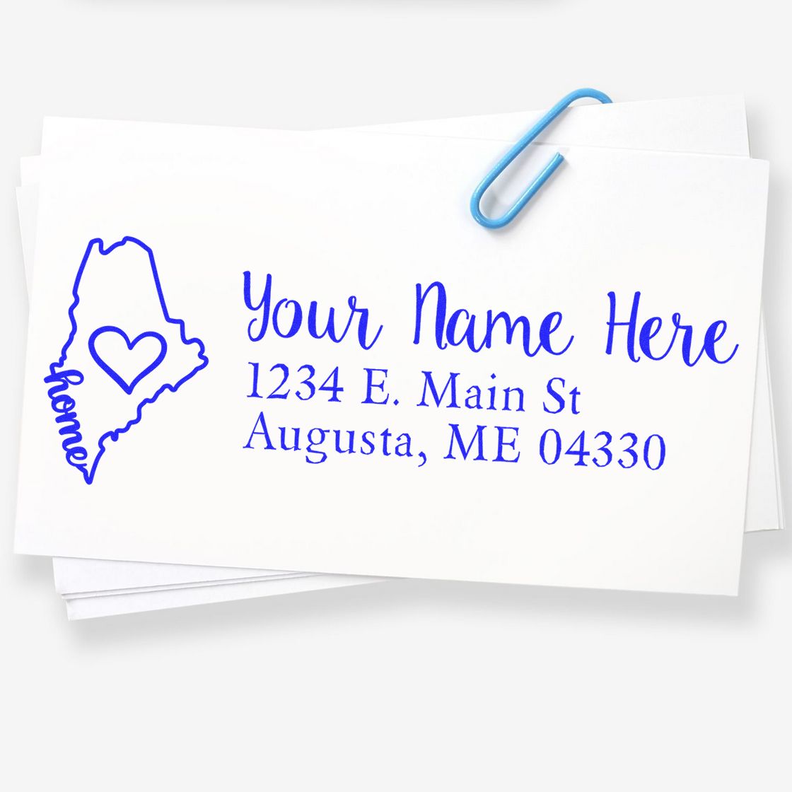 PSI Pre-Inked Personalized Maine State Love Address Stamp on white paper, featuring a blue outline of Maine with a heart and the word home, alongside customizable address text.