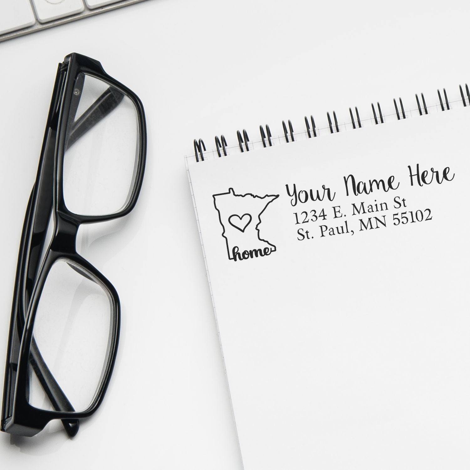 Wood Handle Minnesota Custom Address Rubber Stamp on a notepad with a printed address, next to black glasses and a keyboard, showcasing its elegant design and personalized touch.