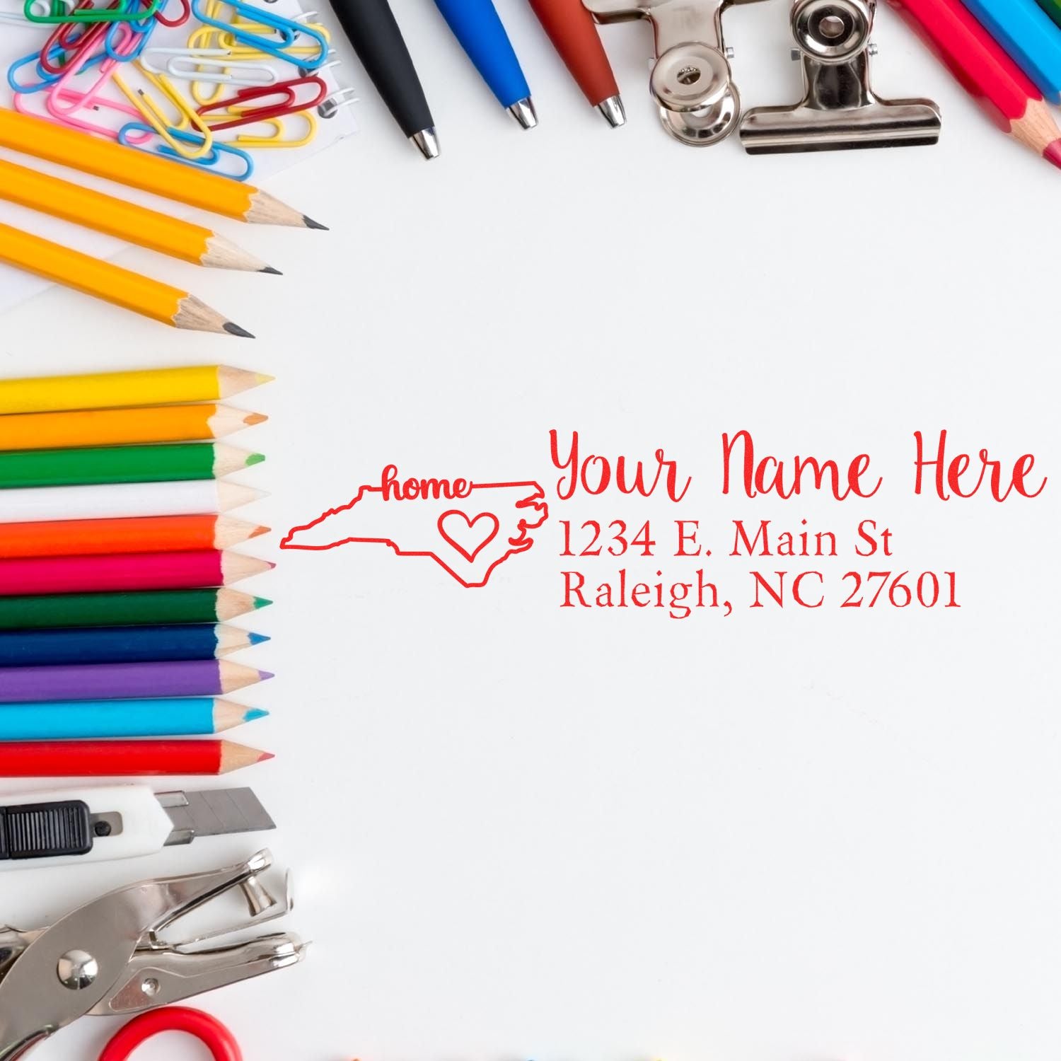 Colorful stationery surrounds a stamped address featuring the North Carolina Self-Inking State Love Address Stamp, showcasing a heart and state outline with customizable text.