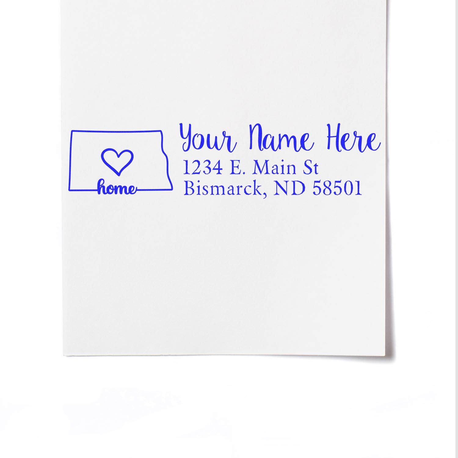 PSI Pre-Inked Personalized North Dakota State Love Address Stamp on white paper, featuring a heart inside the state outline and sample text: Your Name Here, 1234 E. Main St, Bismarck, ND 58501.