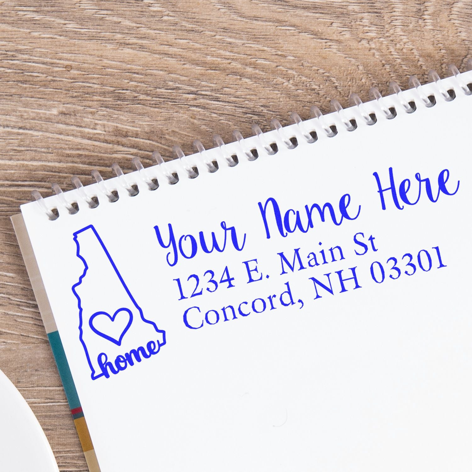 New Hampshire Self-Inking State Love Address Stamp on notepad, featuring a heart design and customizable address in blue ink, perfect for personalizing mail with a touch of home.