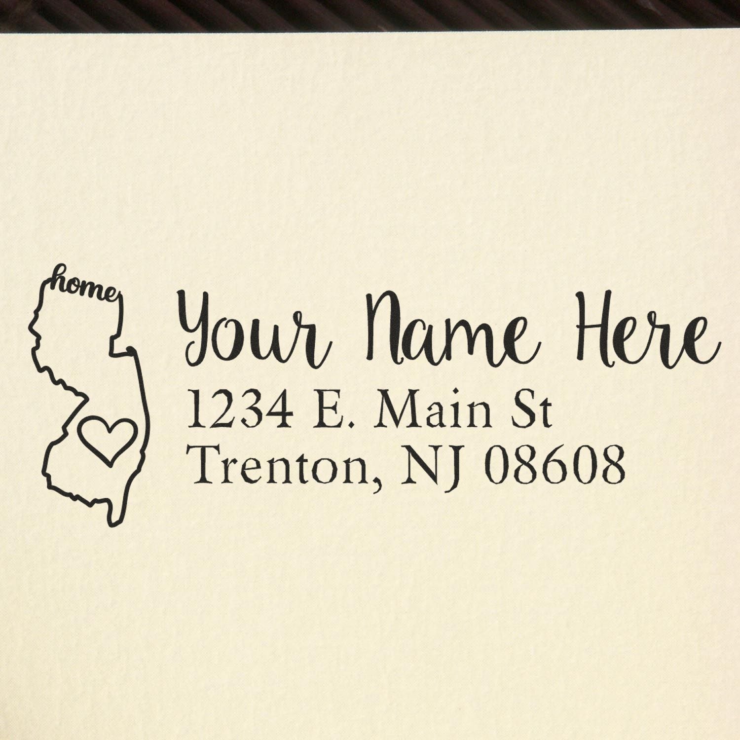 Wood Handle New Jersey Custom Address Rubber Stamp on paper, featuring a map outline with home text and heart, personalized with name and address: 1234 E. Main St, Trenton, NJ 08608.