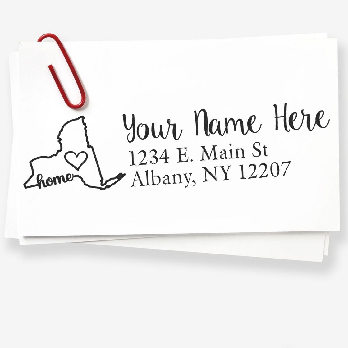 New York Self-Inking State Love Address Stamp on white paper with a red paperclip, featuring a heart inside the state outline and sample address text. Perfect for personalized mailings.