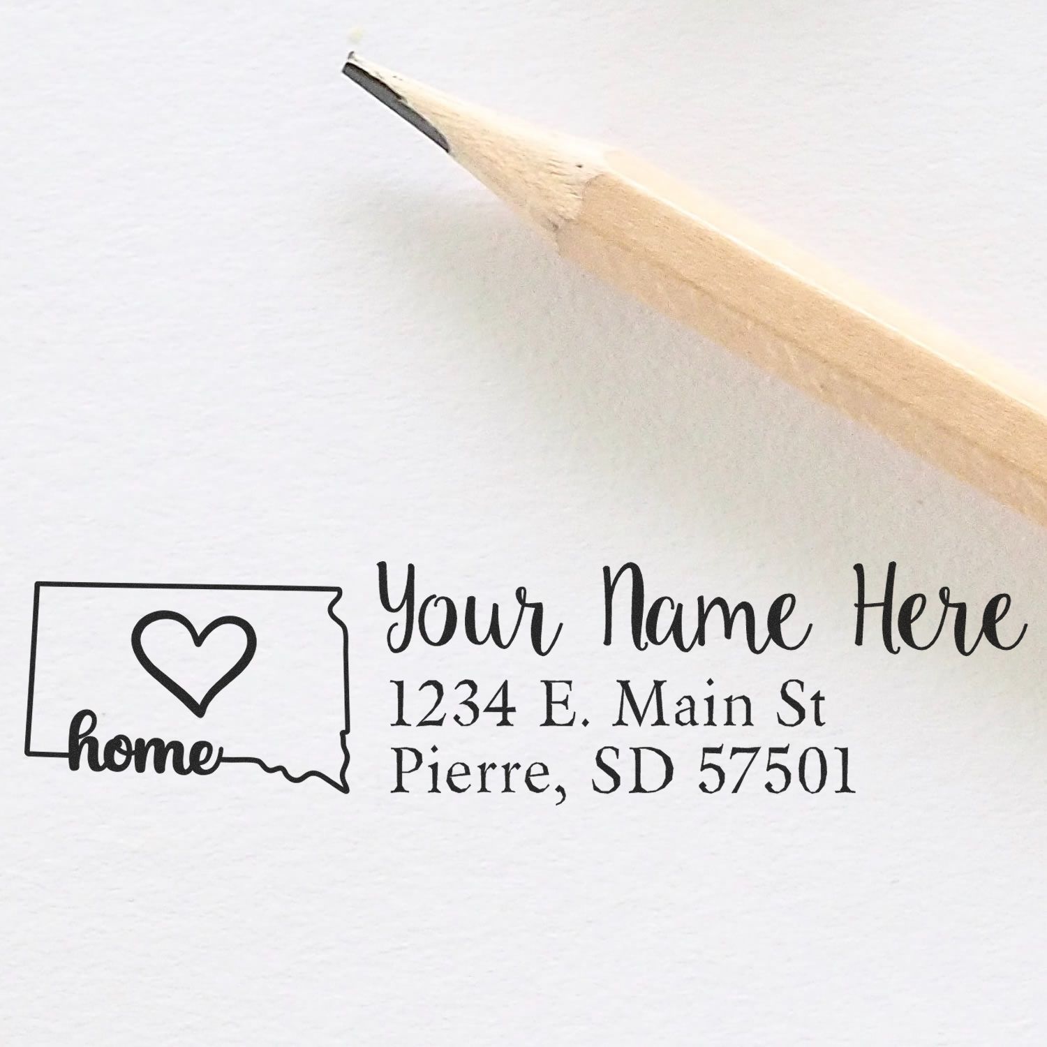 PSI Pre-Inked Personalized South Dakota State Love Address Stamp on white paper with a pencil. Features a heart inside the state outline, customizable name, and address text.