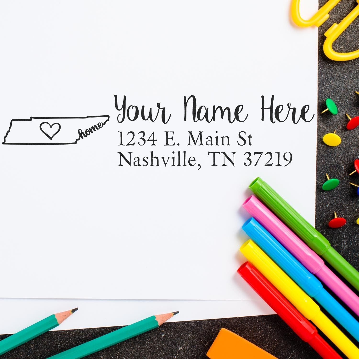 Wood Handle Tennessee Custom Address Rubber Stamp on white paper with colorful pens and push pins. The stamp features a heart and the word home inside the Tennessee state outline, with sample address text.