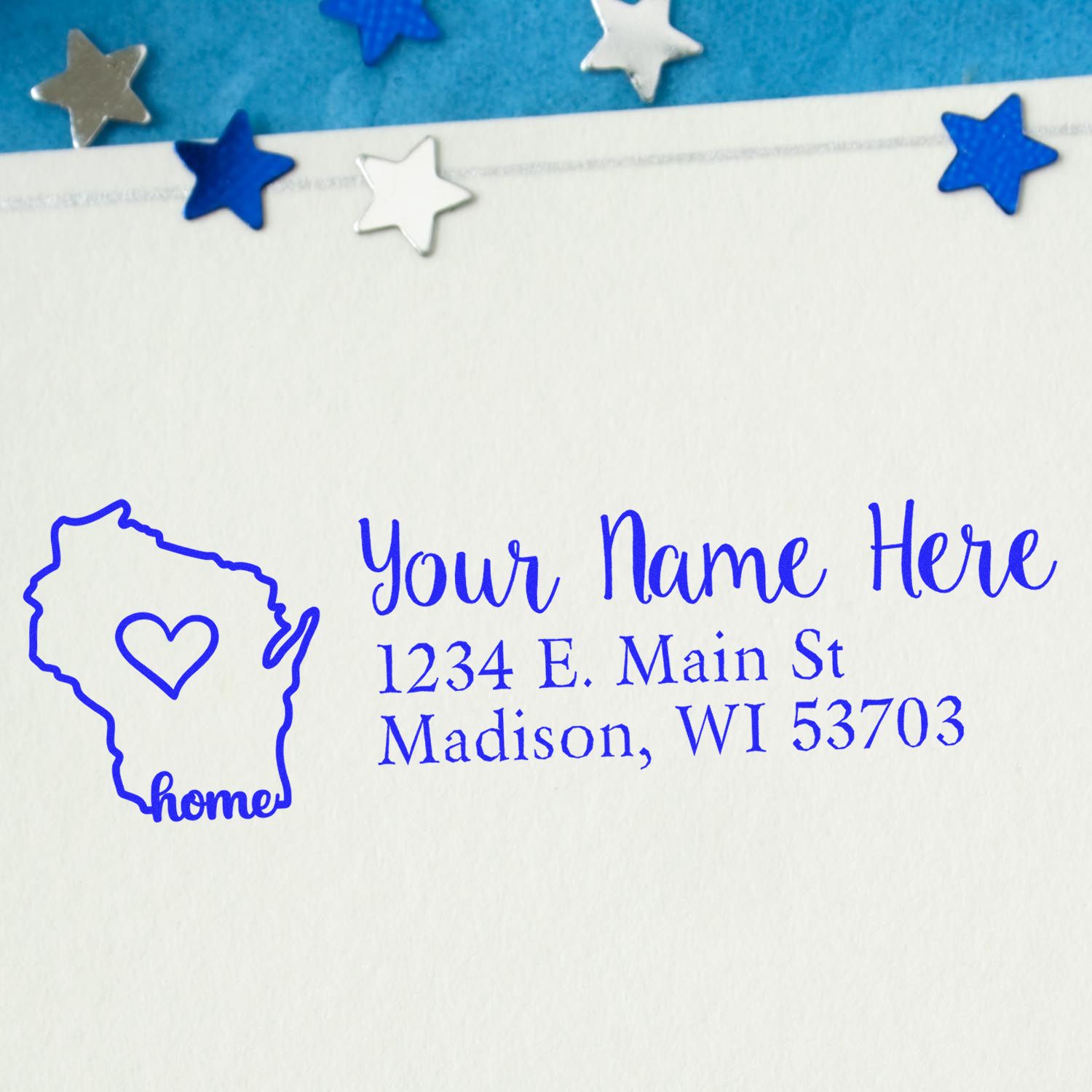 PSI Pre-Inked Personalized Wisconsin State Love Address Stamp on an envelope, featuring a heart inside the state outline with stars around. Text reads Your Name Here, 1234 E. Main St, Madison, WI 53703.