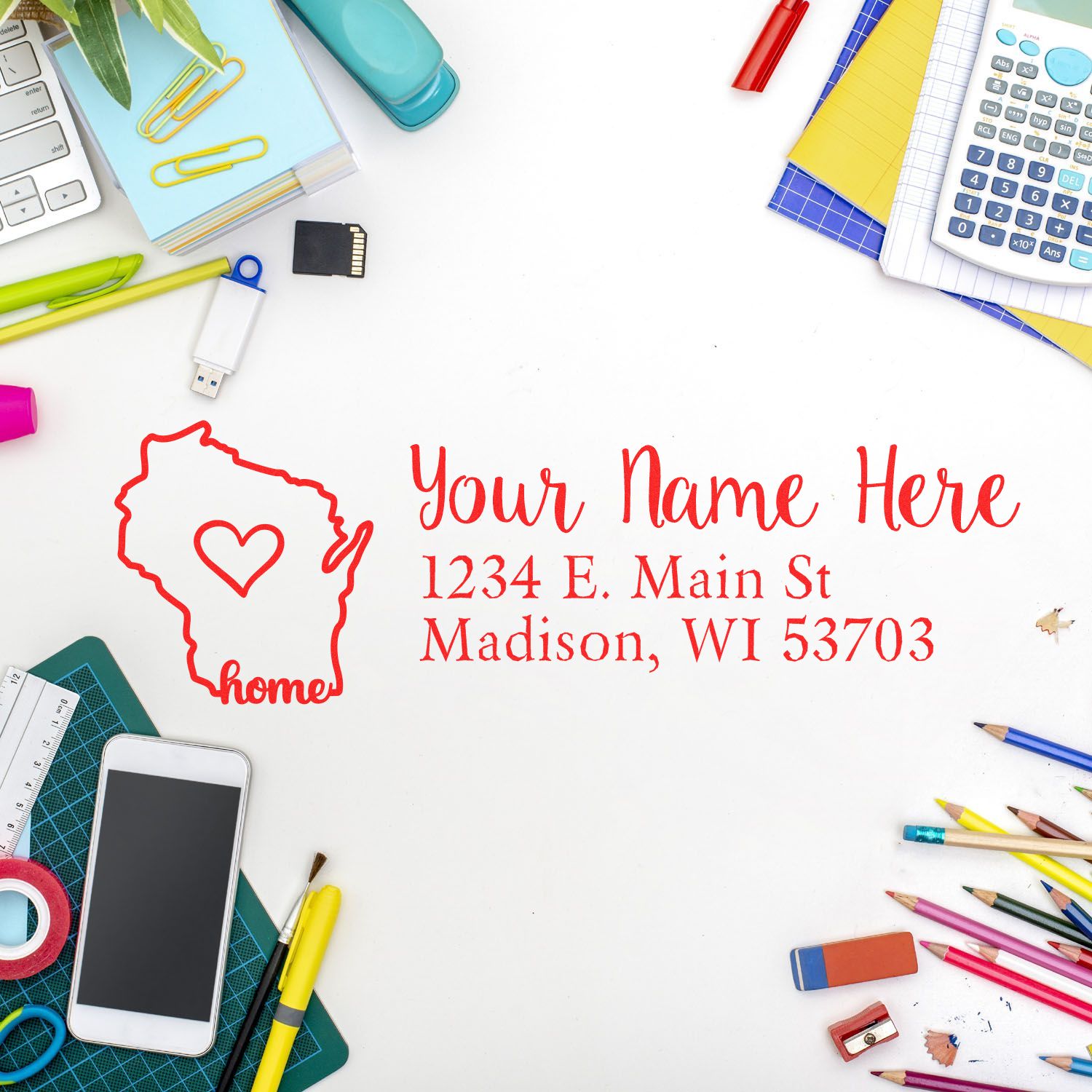 A desk with colorful stationery surrounds a stamped address featuring a Wisconsin outline and heart. The Wood Handle Wisconsin Custom Address Rubber Stamp is prominently displayed in red.