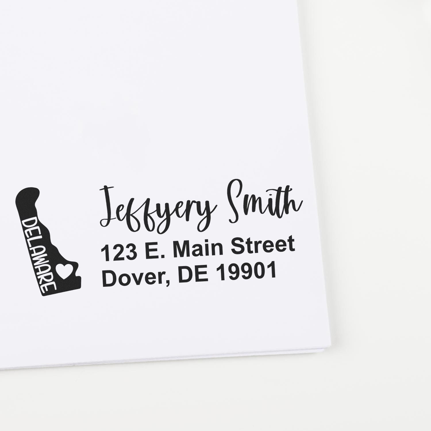 Image of the Slim Delaware Custom Address Stamp for Envelopes, featuring a stamped address with a Delaware state outline and heart, showcasing elegant typography on a white envelope.