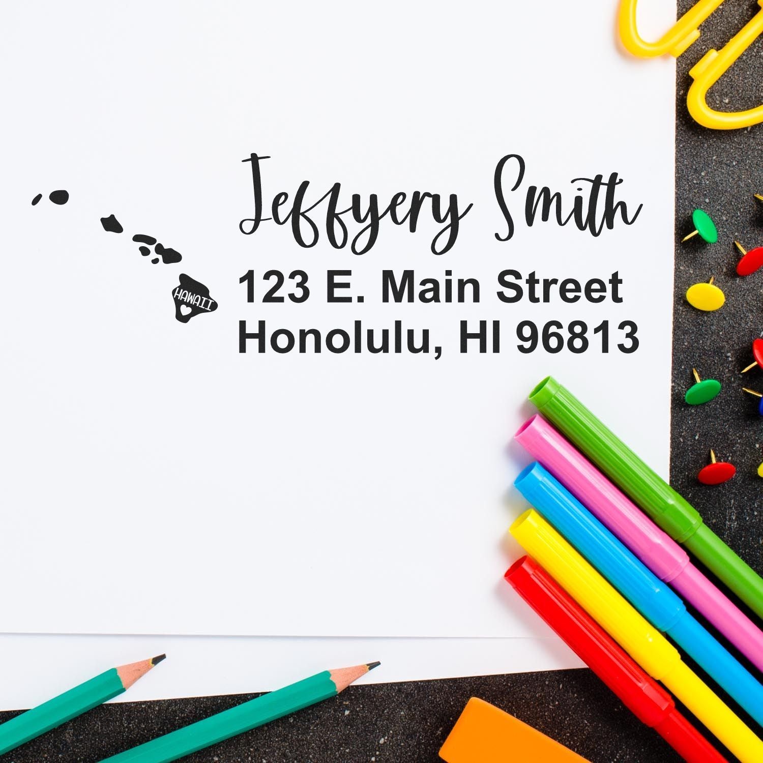 State Love of Hawaii Custom Address Stamp Self-Inking on white paper with colorful pens. Displays Jeffery Smith, 123 E. Main Street, Honolulu, HI 96813 with a Hawaii map design.