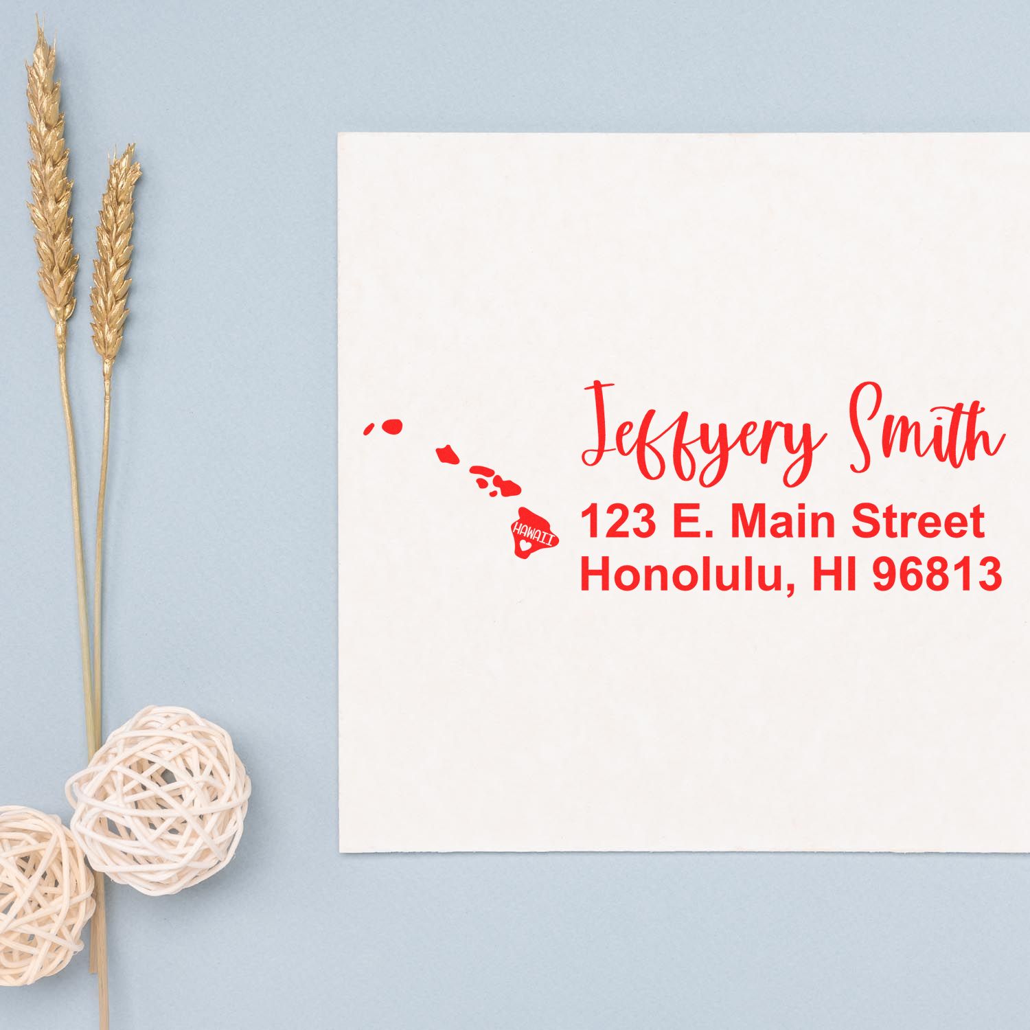 Hawaii State Love Personalized Address Stamp on a white envelope with red text showing a sample address. Decorative elements include wheat stalks and woven balls on a light blue background.