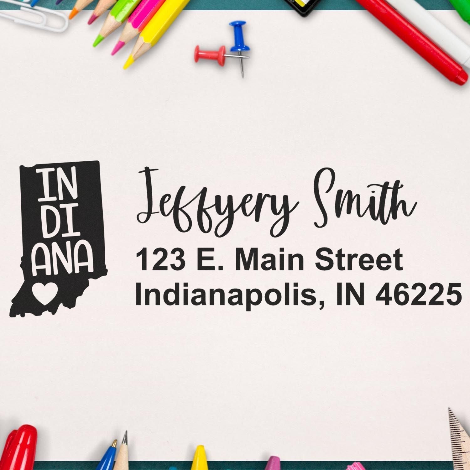 Slim Indiana Custom Address Stamp for Envelopes displayed on paper with colorful stationery around. The stamp features a state outline with a heart and personalized address details.