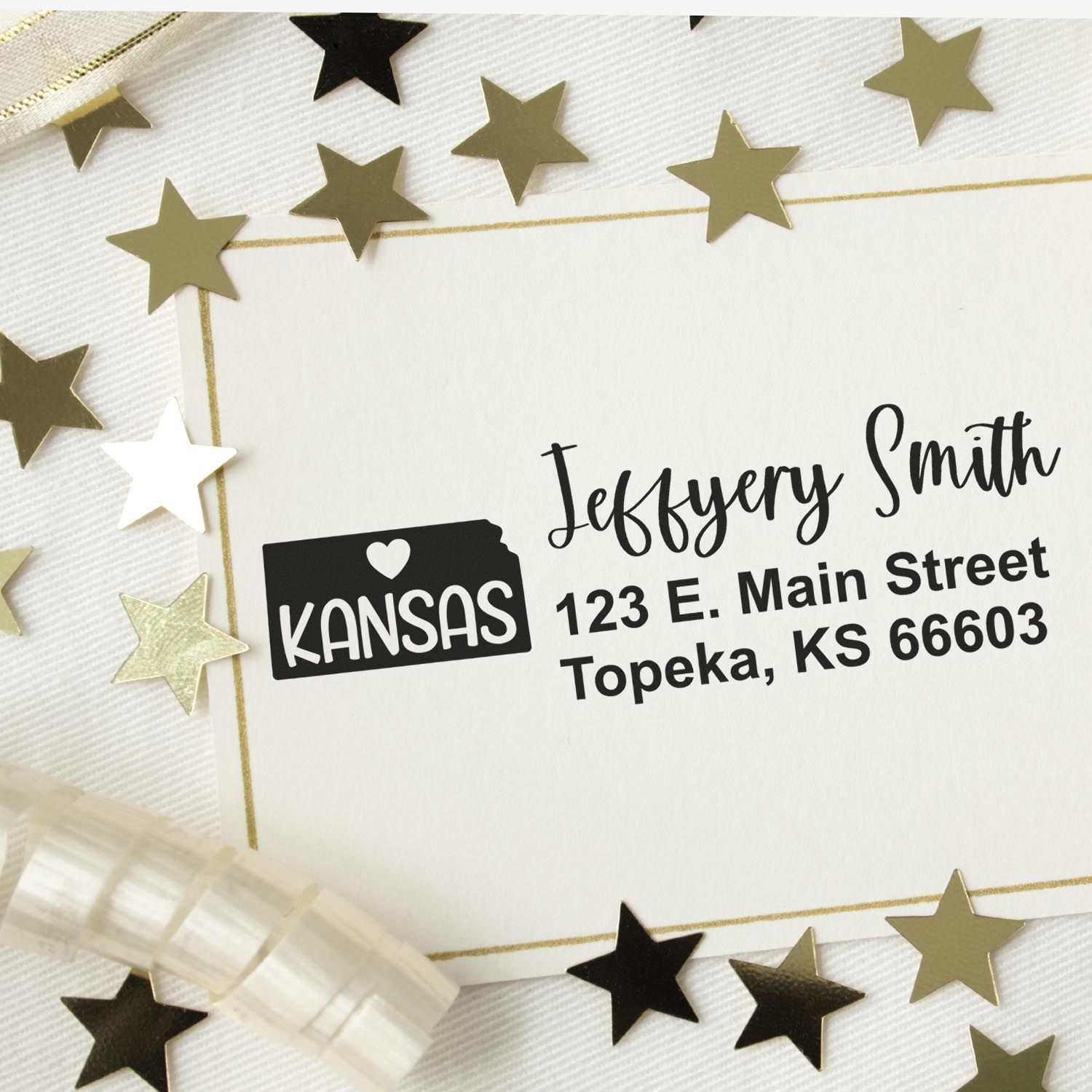 Kansas State Love Personalized Address Stamp on an envelope with gold stars and ribbon. The stamp features a heart and the word Kansas alongside a sample address in elegant script.