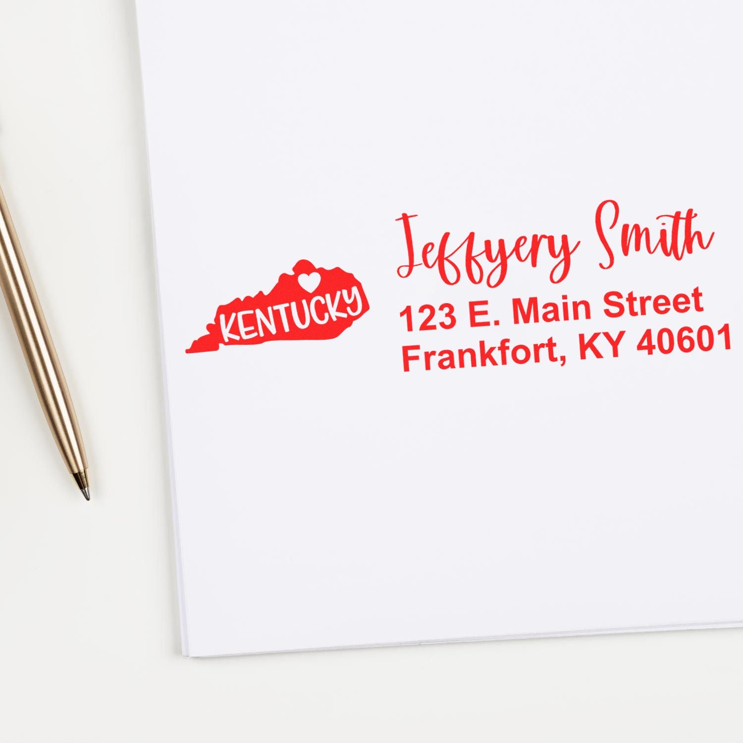 Kentucky State Love Personalized Address Stamp in red ink on white paper, featuring a heart design and sample address for Jeffery Smith in Frankfort, KY. Pen placed beside the stamped address.