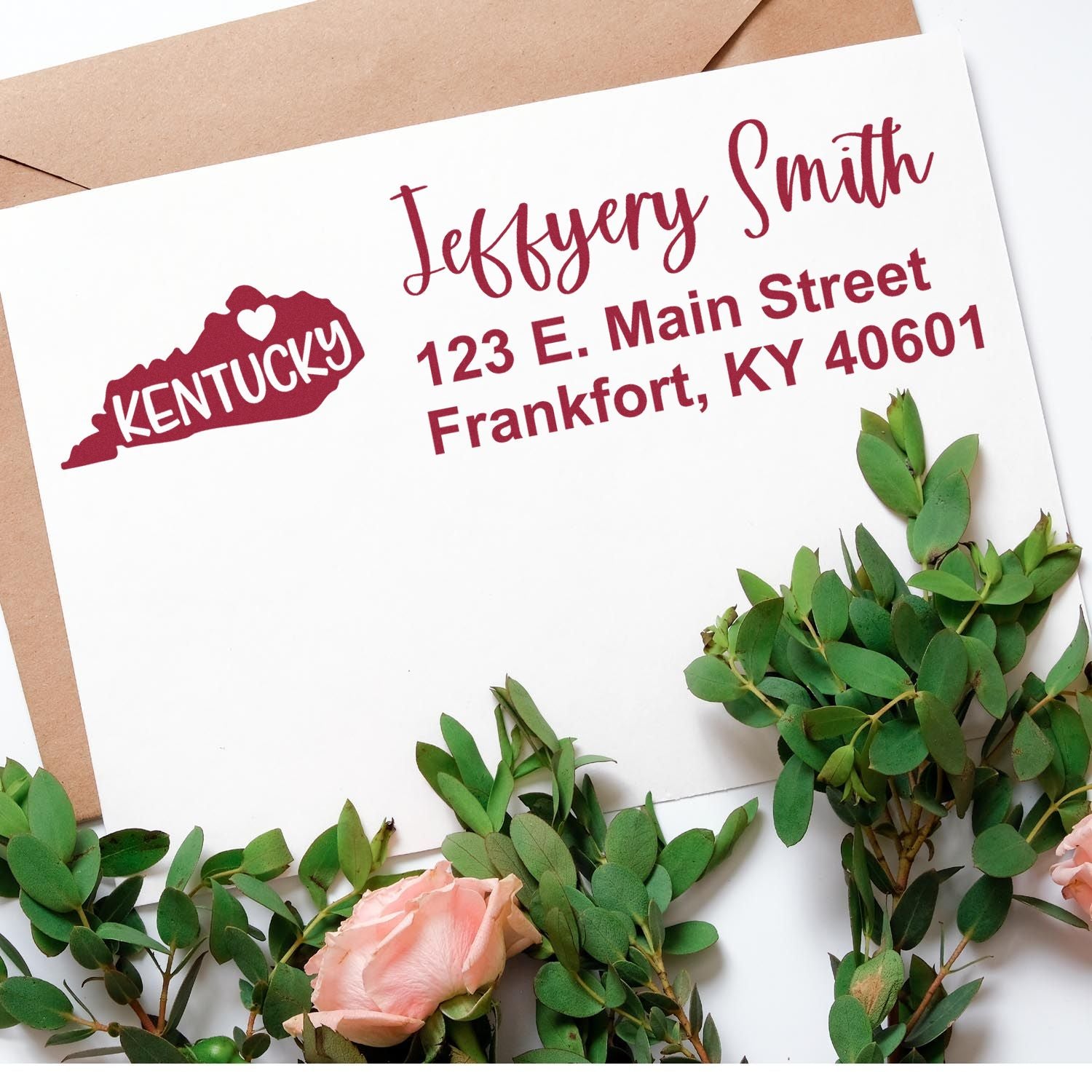 PSI Pre-Inked Kentucky State Love Customized Address Stamp on an envelope with a Kentucky outline and heart, surrounded by green leaves and pink roses.