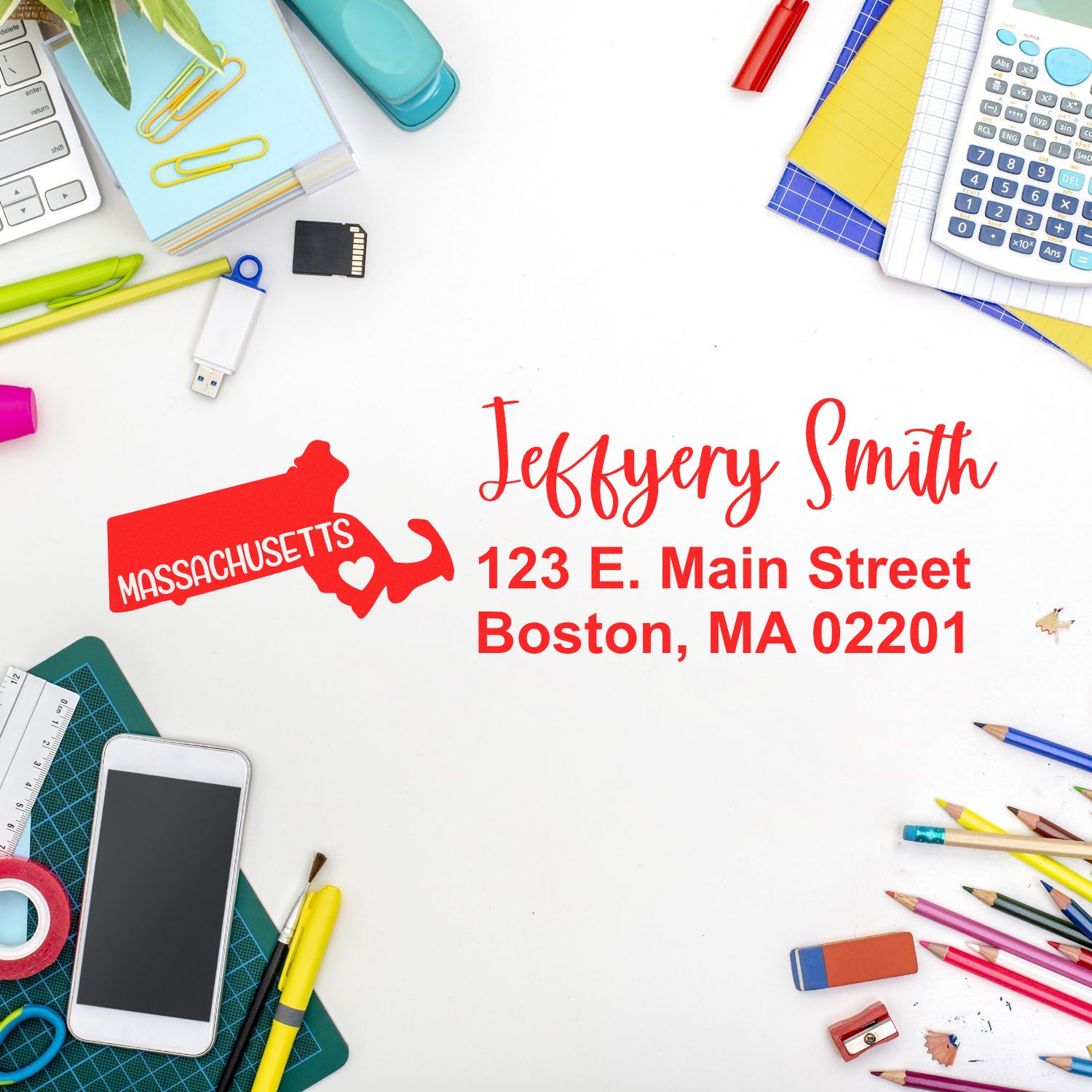 Desk with colorful stationery, phone, and Massachusetts State Love Personalized Address Stamp showing Jeffery Smith, 123 E. Main Street, Boston, MA 02201 in red on white paper.