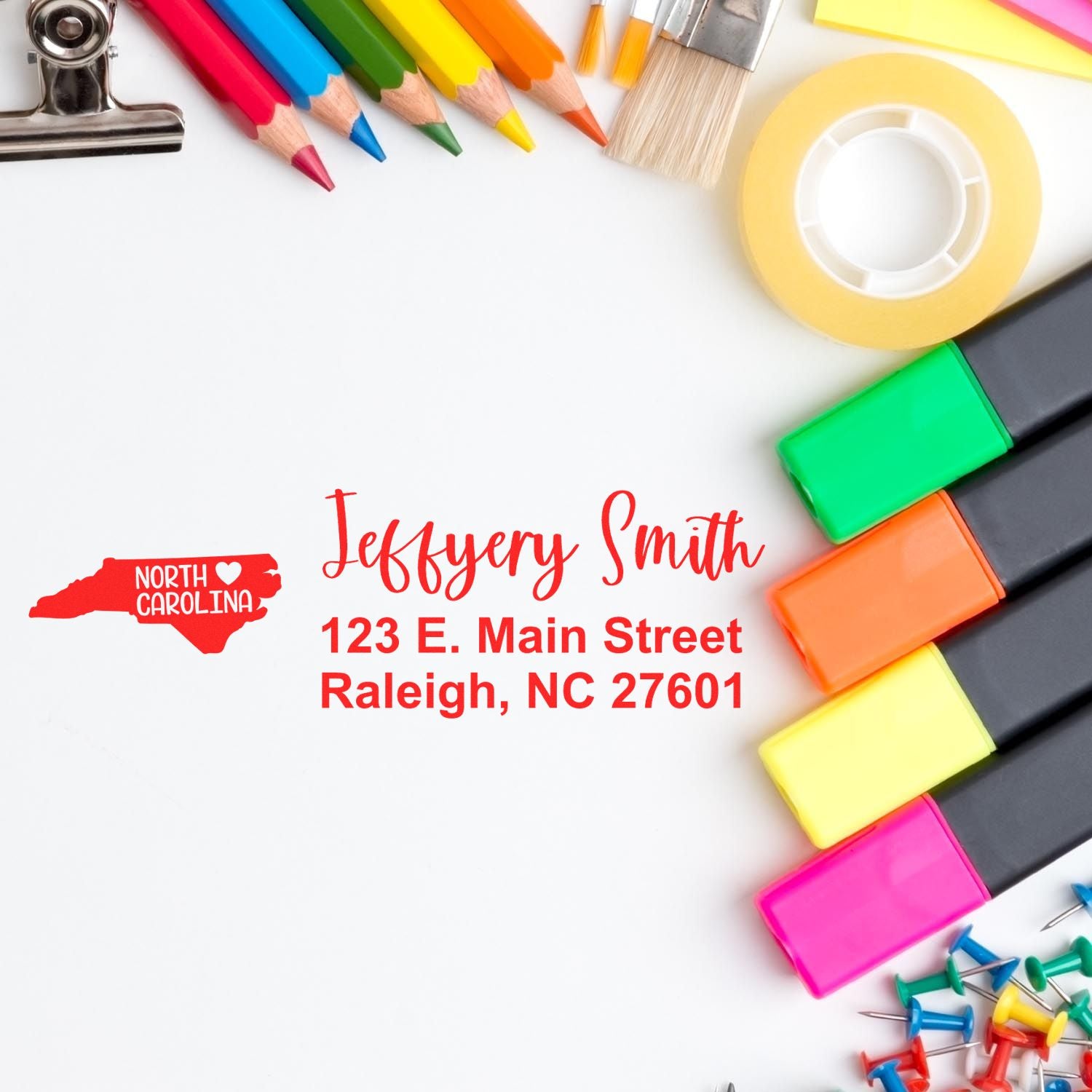 A PSI Pre-Inked North Carolina State Love Customized Address Stamp on paper with colorful stationery items like markers, pencils, and tape surrounding it.