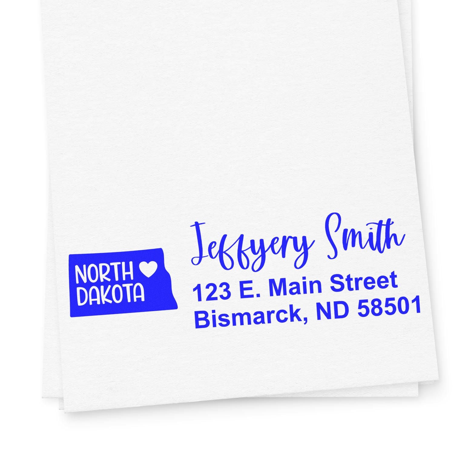 North Dakota State Love Personalized Address Stamp in blue ink on white paper, featuring a heart within the state outline and sample address: Jeffery Smith, 123 E. Main Street, Bismarck, ND 58501.