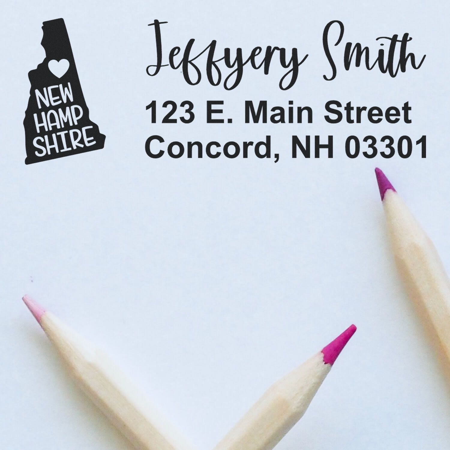 State Love of New Hampshire Custom Address Stamp Self-Inking on white paper with pink-tipped pencils. Displays New Hampshire graphic and address: Jeffery Smith, 123 E. Main Street, Concord, NH 03301.