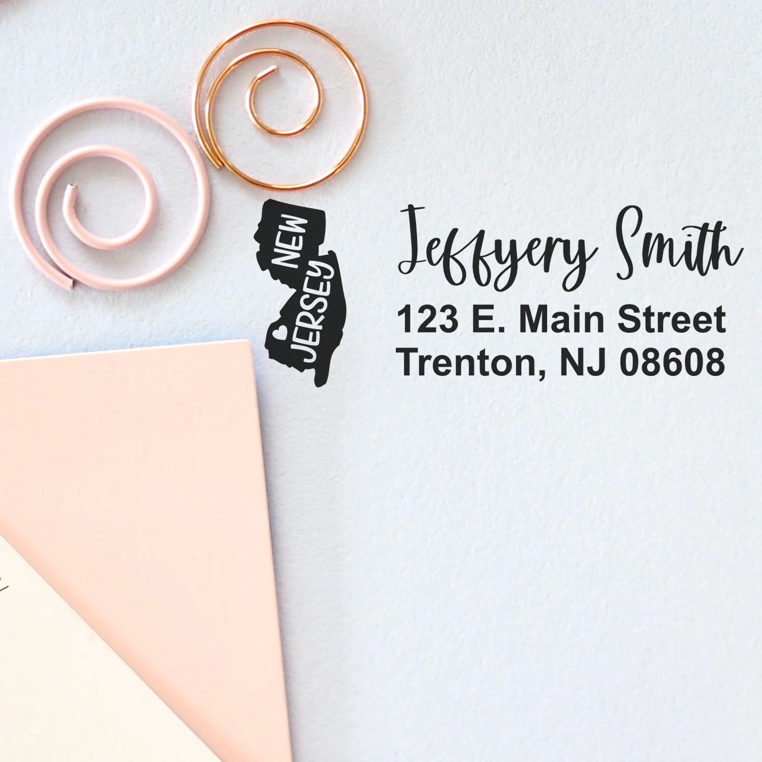 State Love of New Jersey Custom Address Stamp Self-Inking displayed on paper with 'Jeffery Smith, 123 E. Main Street, Trenton, NJ 08608' next to decorative spirals.