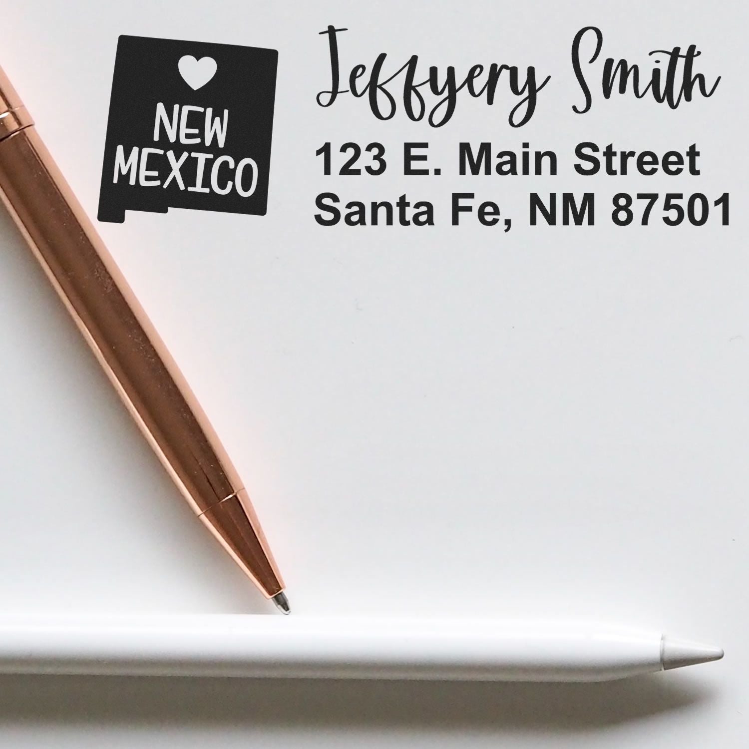 Image of a New Mexico State Love Personalized Address Stamp on white paper, featuring a heart and state outline, with the address 123 E. Main Street, Santa Fe, NM 87501 in elegant script.