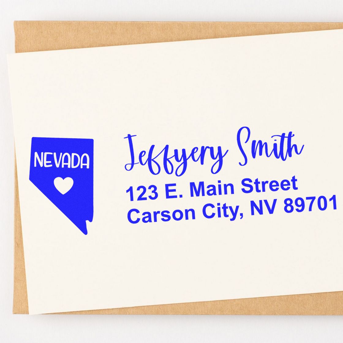 Slim Nevada Custom Address Stamp for Envelopes displayed on a white card with blue text, featuring a Nevada state outline and heart. Placed on a brown envelope.