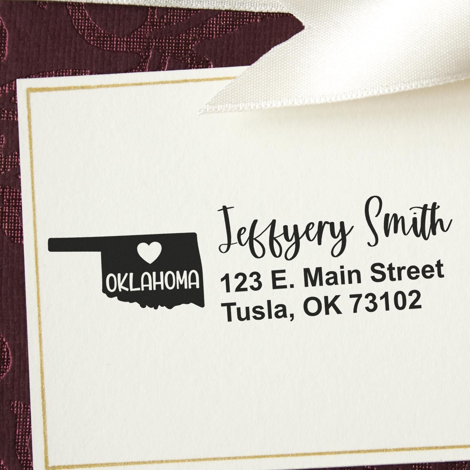 Slim Oklahoma Custom Address Stamp for Envelopes displayed on a white card with a maroon background. The stamp features a heart and the word Oklahoma in a state outline, with sample address text.