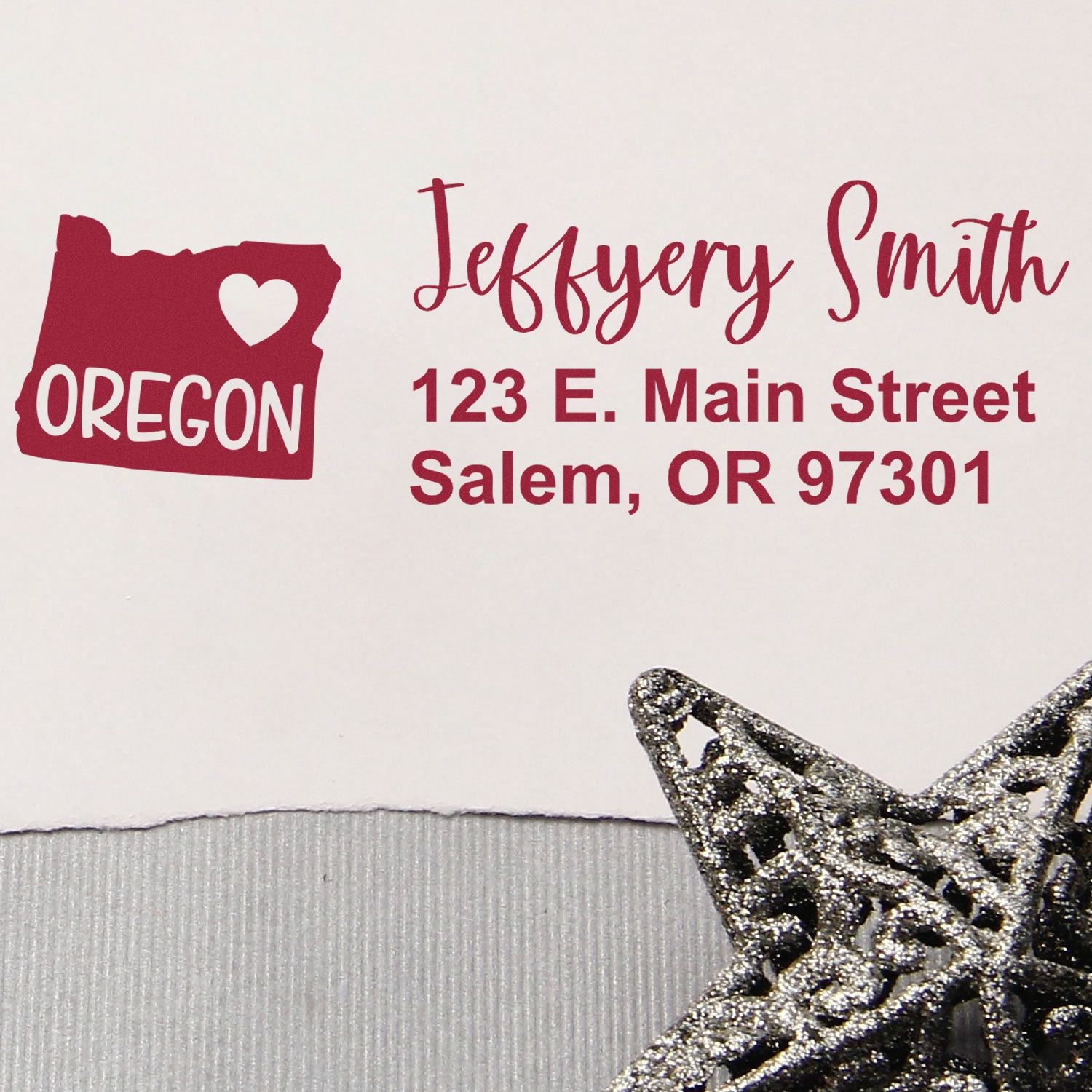 Oregon State Love Personalized Address Stamp on an envelope with a red Oregon map and heart design, featuring the name Jeffery Smith and an address. A silver decorative star is in the foreground.