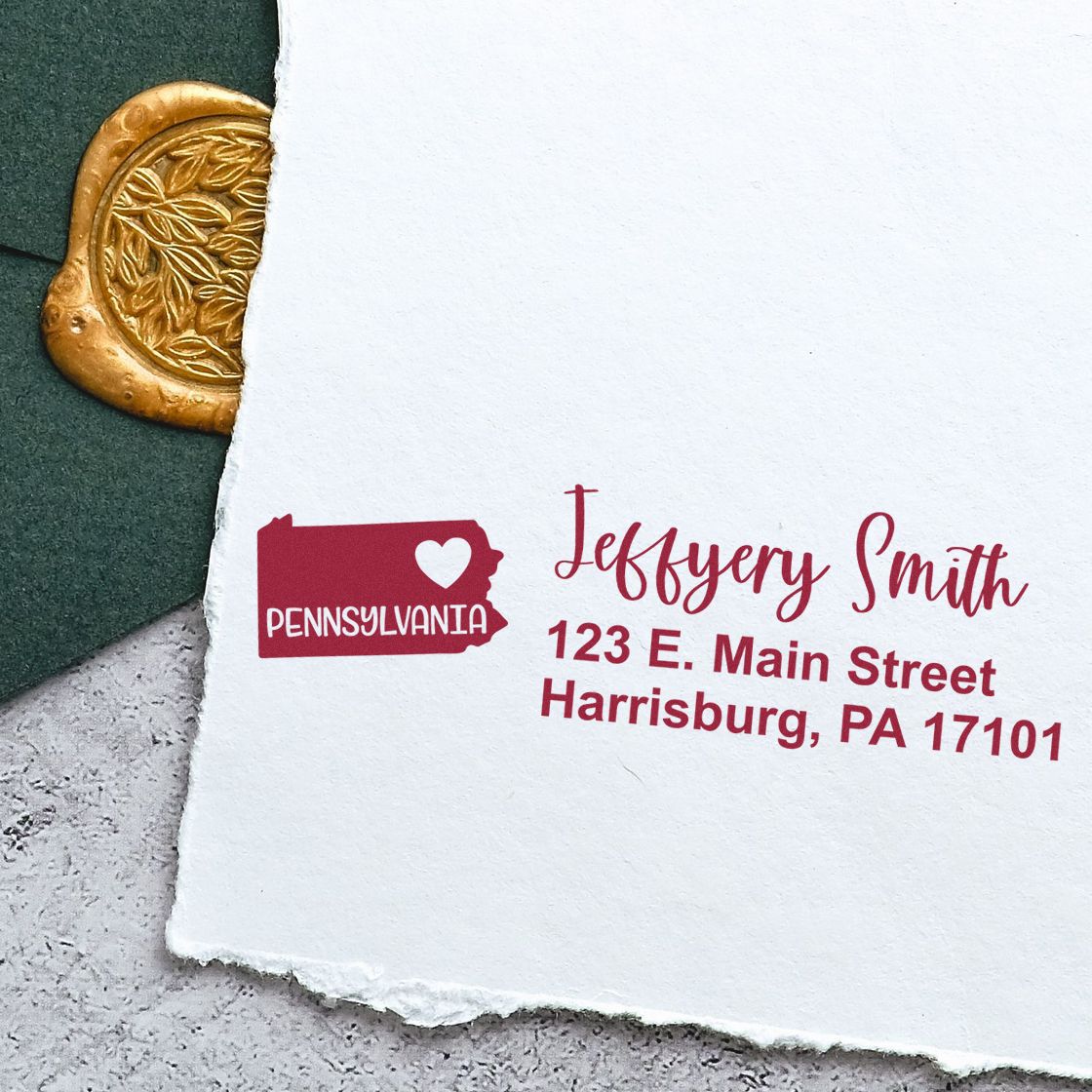 Pennsylvania State Love Personalized Address Stamp on white paper with a green envelope and gold wax seal. The stamp features a heart and state outline with red text for a custom address.