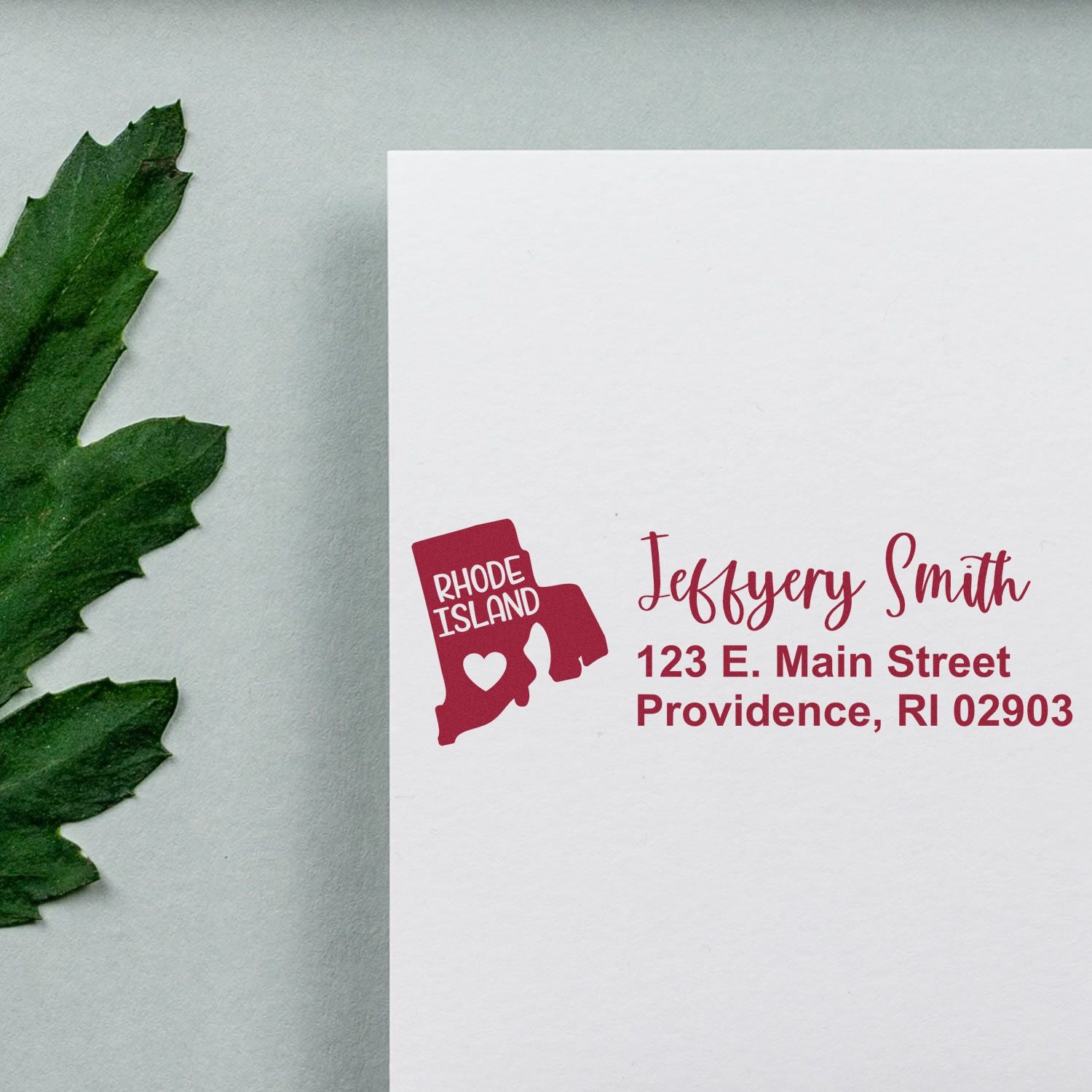 State Love of Rhode Island Custom Address Stamp Self-Inking on white paper with a green leaf. Displays Rhode Island map and personalized address in red ink.