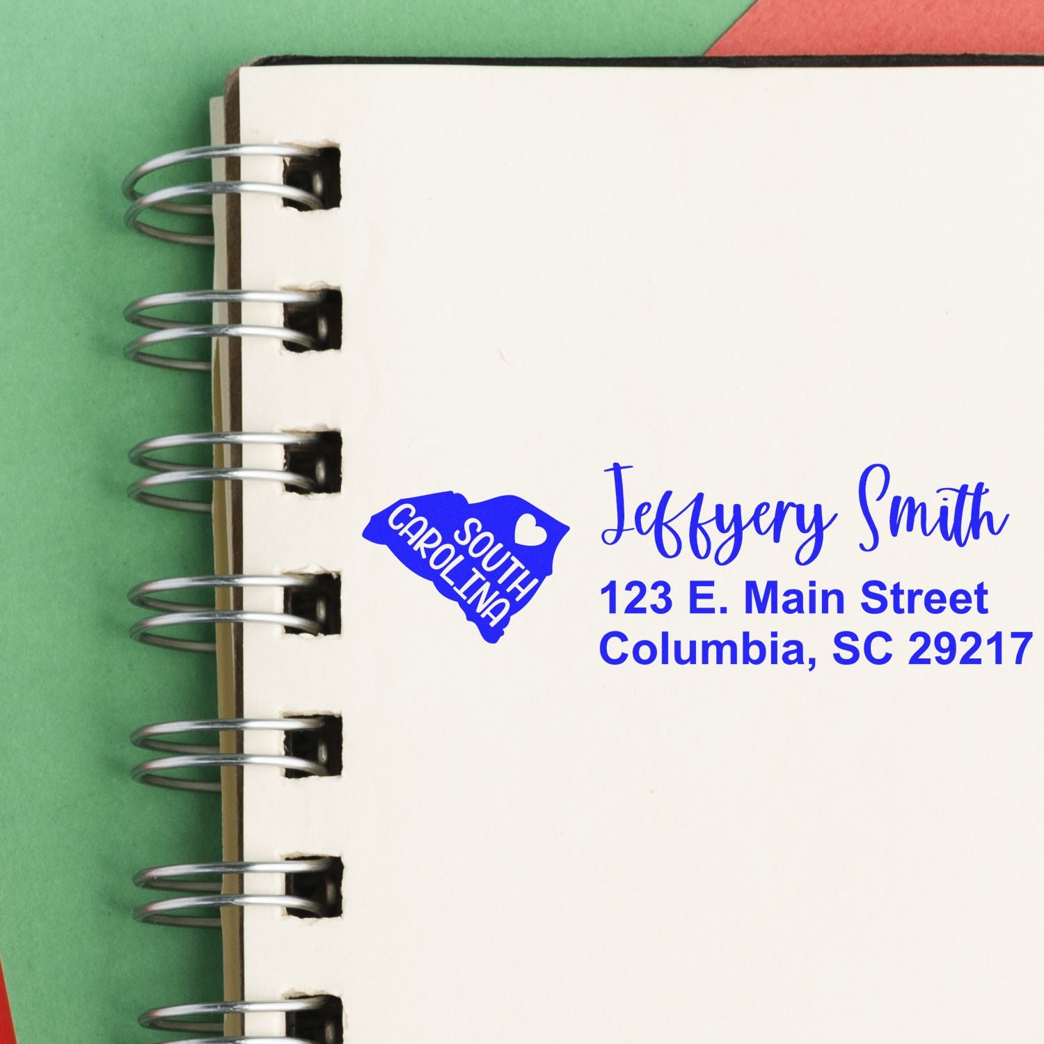 Slim South Carolina Custom Address Stamp for Envelopes displayed on a notebook, featuring a blue state outline and personalized address in elegant font.