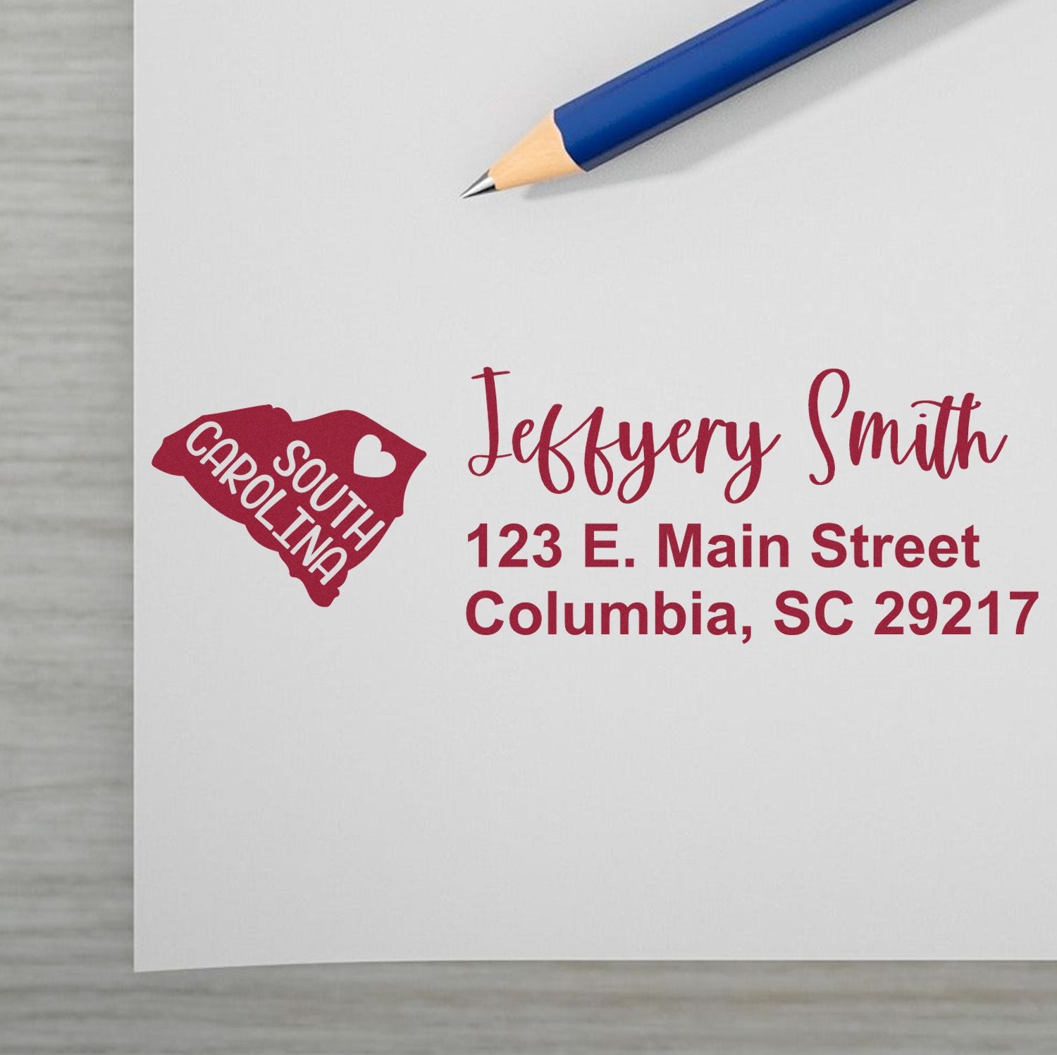 South Carolina State Love Personalized Address Stamp on white paper with red ink, featuring a heart and state outline. Includes name and address in elegant font. Blue pencil nearby.