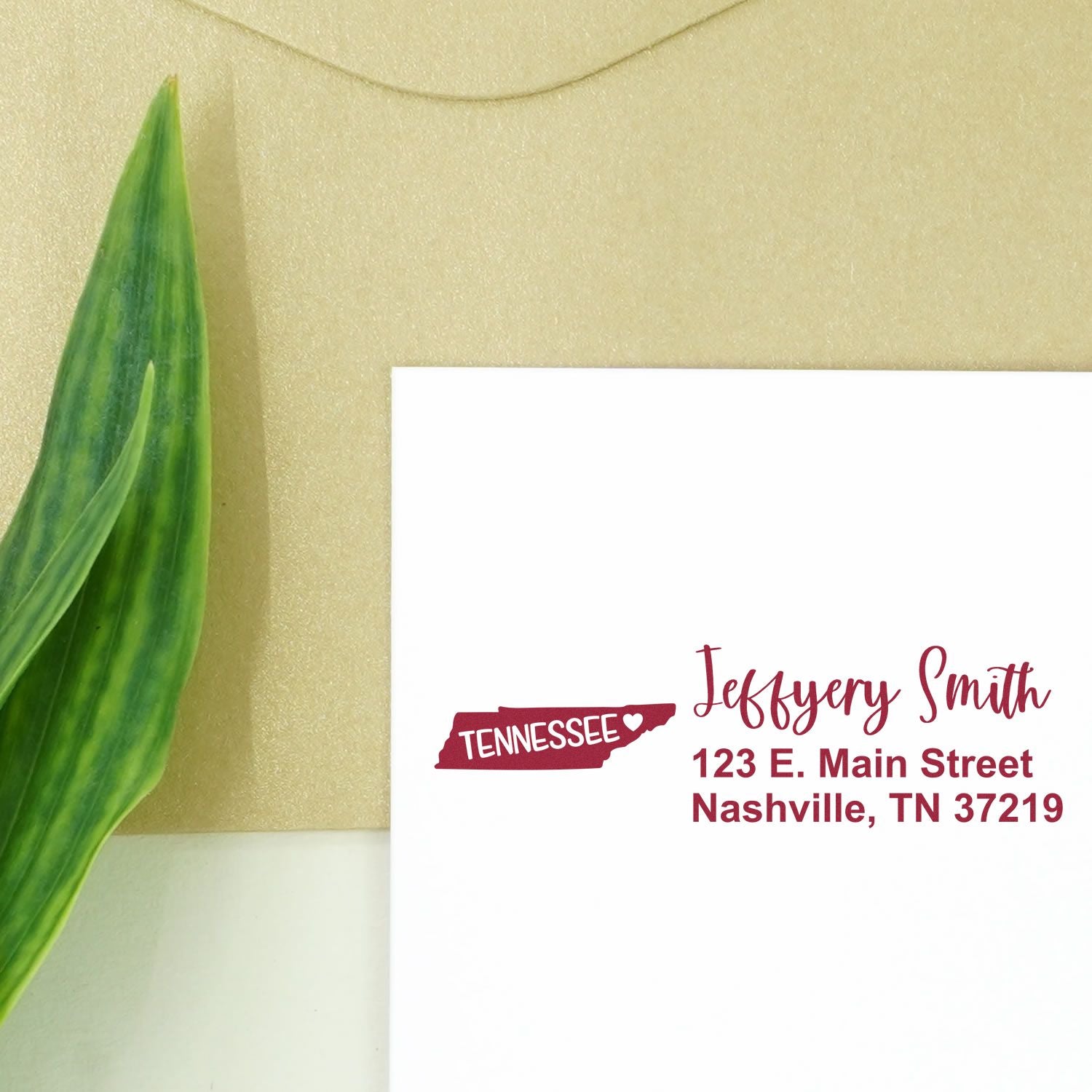 Slim Tennessee Custom Address Stamp for Envelopes displayed on a white card with a beige envelope and green leaf. The stamp features a Tennessee state outline and personalized address in red.