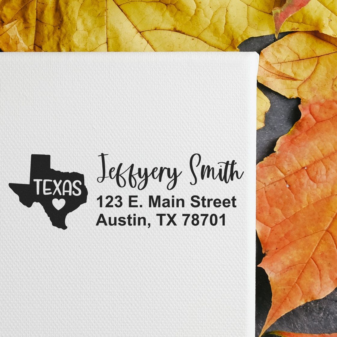 Texas State Love Personalized Address Stamp on white paper with Jeffery Smith, 123 E. Main Street, Austin, TX 78701 text, set against a background of autumn leaves.