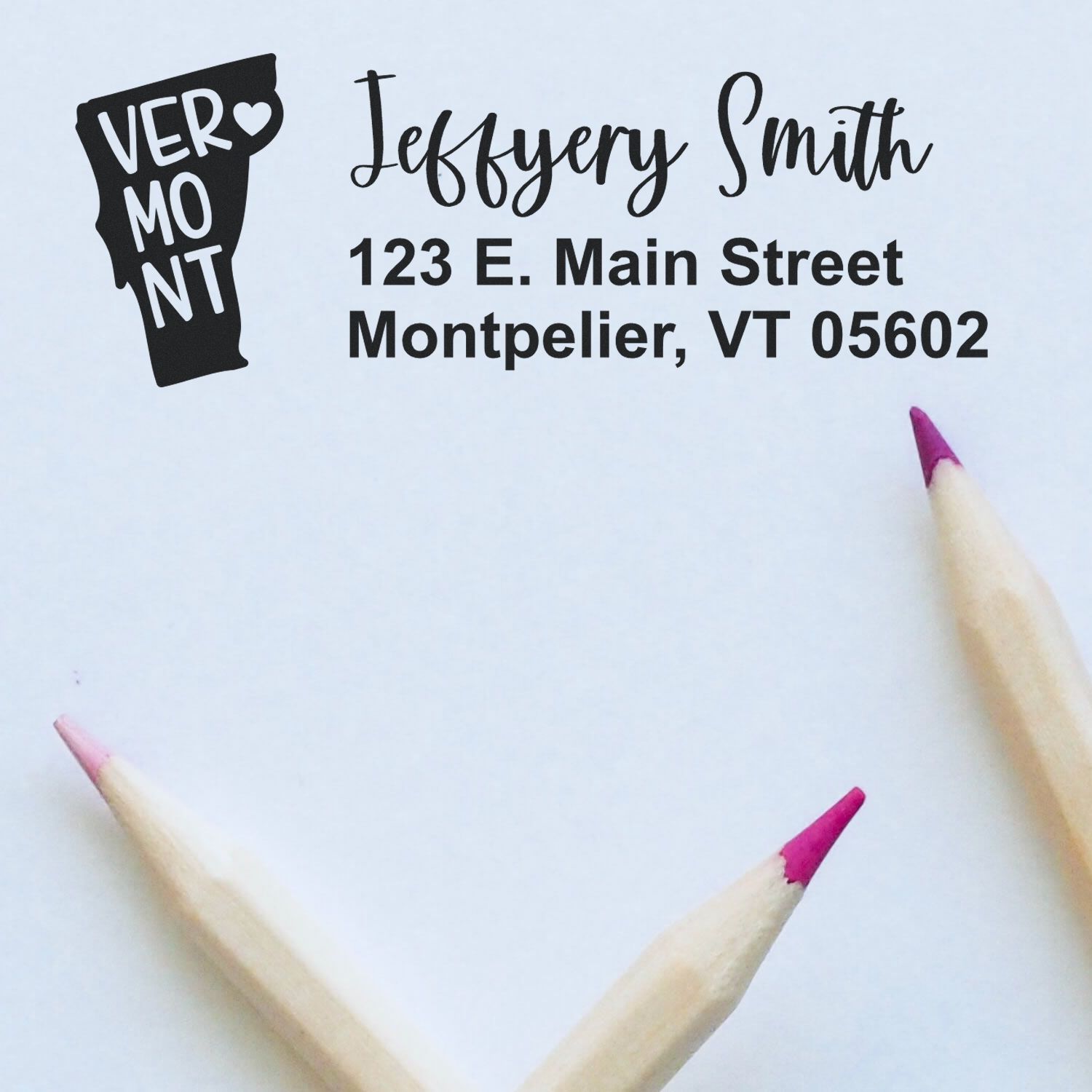 Vermont State Love Personalized Address Stamp featuring a Vermont silhouette with VERMONT text, alongside a sample address. Two pink-tipped pencils frame the image on a light background.