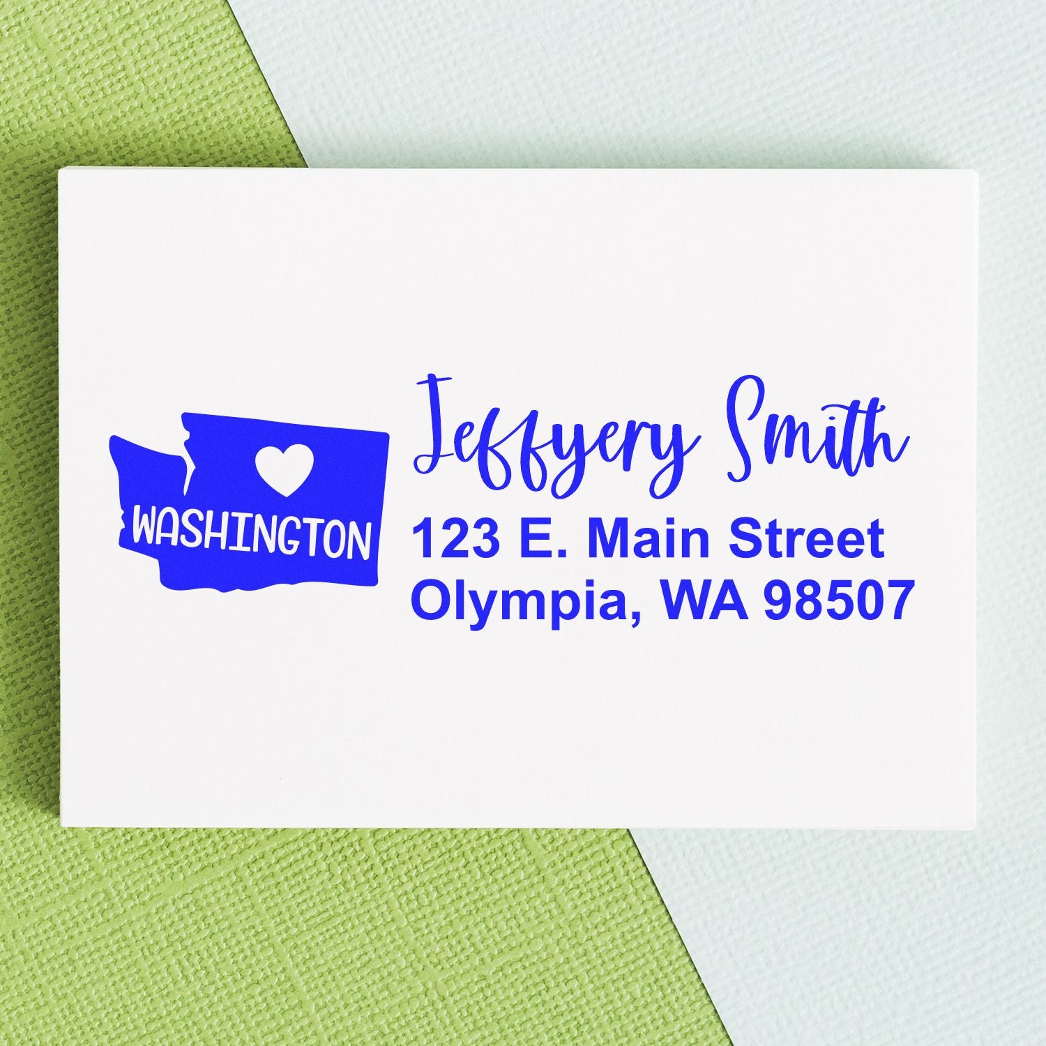 Washington State Love Personalized Address Stamp on an envelope, featuring a heart and state outline with blue text: Jeffery Smith, 123 E. Main Street, Olympia, WA 98507.