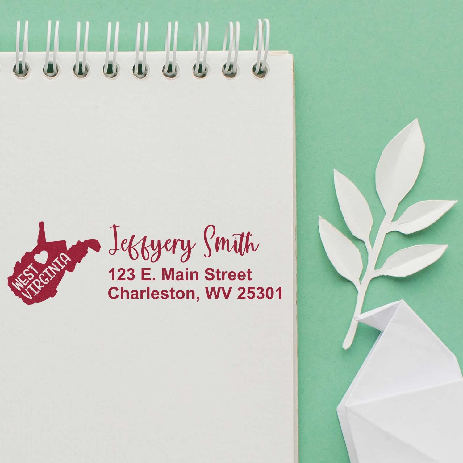 West Virginia State Love Personalized Address Stamp on notepad with green background and paper leaf, featuring a red state outline and custom address text.