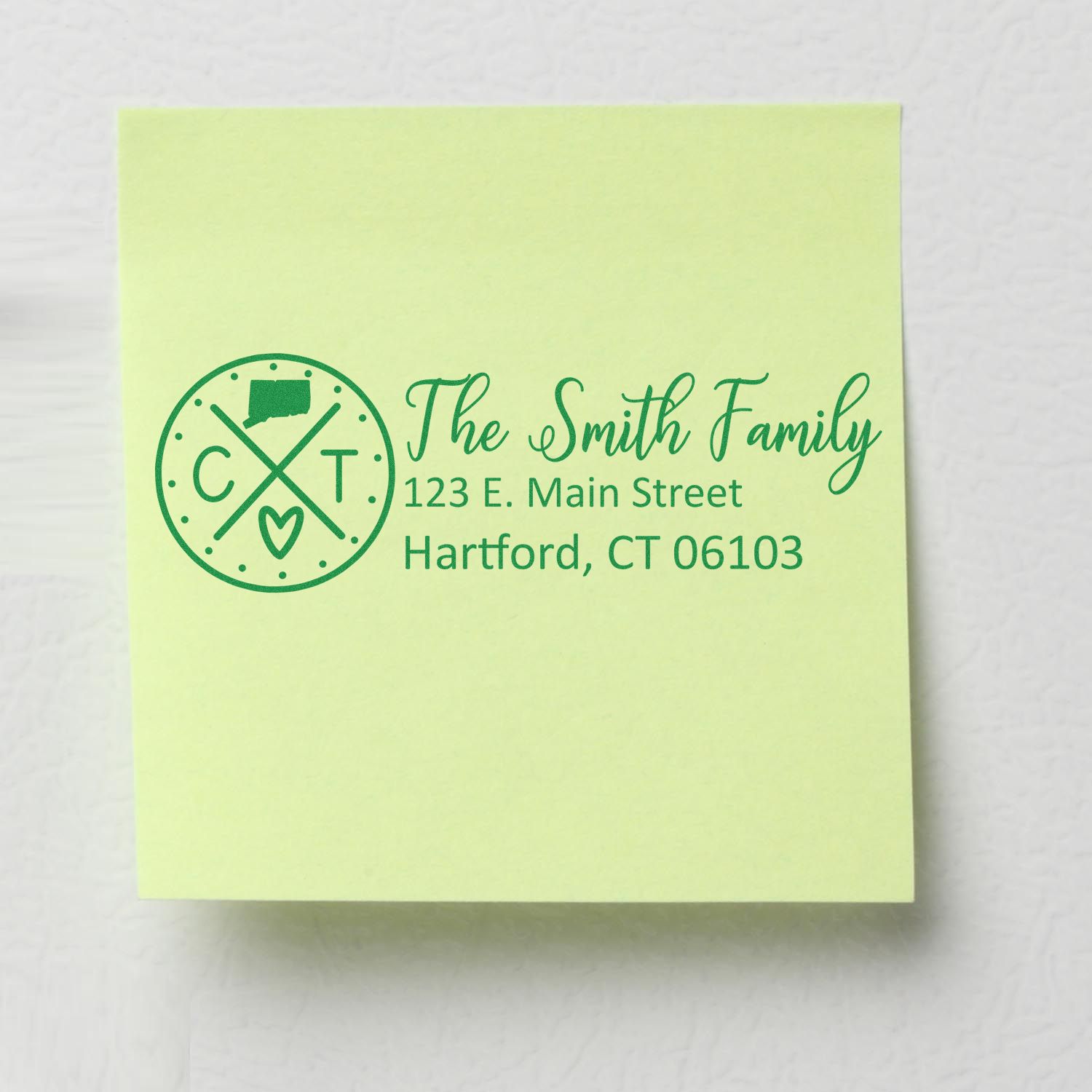 Slim Connecticut Customized Pre-Inked Address Stamp on a green sticky note, displaying The Smith Family, 123 E. Main Street, Hartford, CT 06103 in elegant green font.