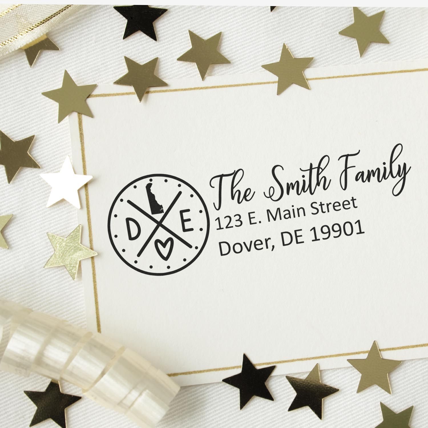 Slim Delaware Customized Pre-Inked Address Stamp on a card with The Smith Family and address, surrounded by gold stars and ribbon on a white background.