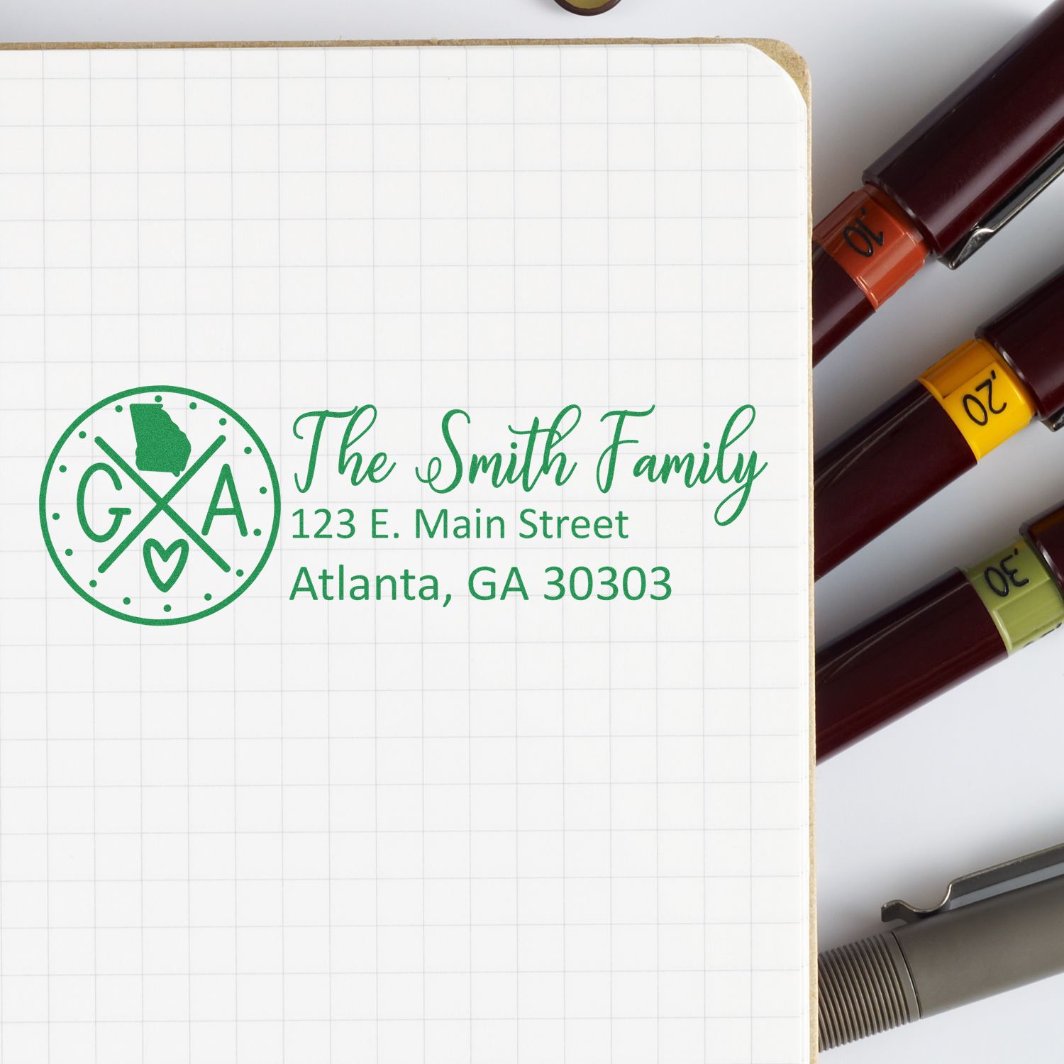 Georgia State Pride Customized Address Stamp on a notebook page, featuring The Smith Family with an address in green ink, surrounded by pens.