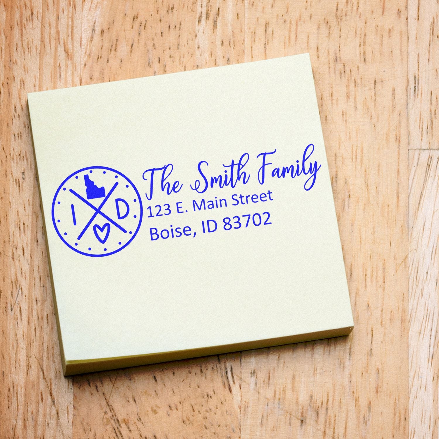 Idaho State Pride Customized Address Stamp on a notepad, featuring a circular design with 'ID' and a heart, personalized with 'The Smith Family' and an address in Boise, ID.